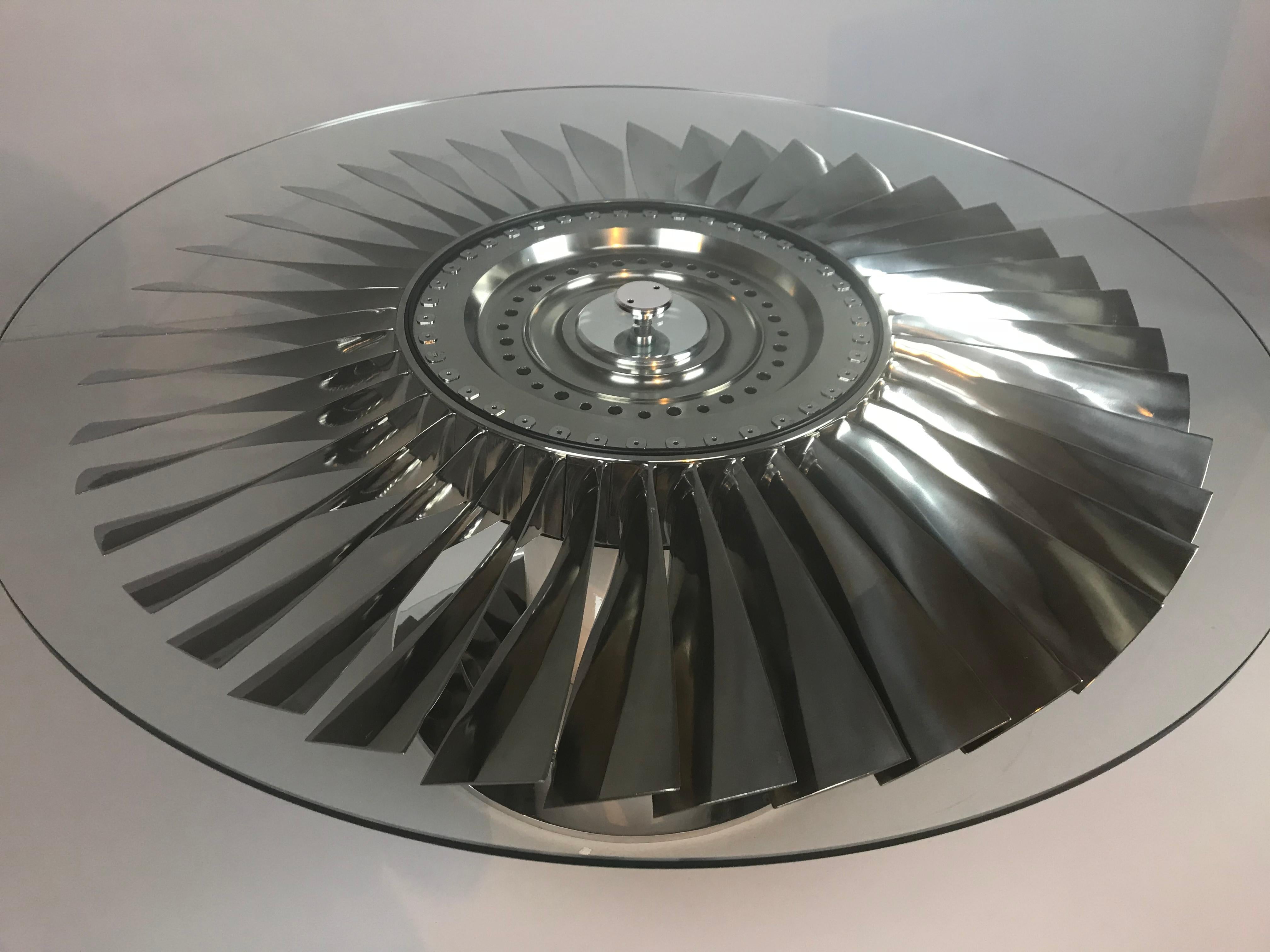 A simply stunning coffee table with 40 polished titanium blades, positioned within its original hub, on a polished custom made base, underneath glass. Practical and unique.

The fan used to make this piece is from a 737 jet aircraft. 
Measures: