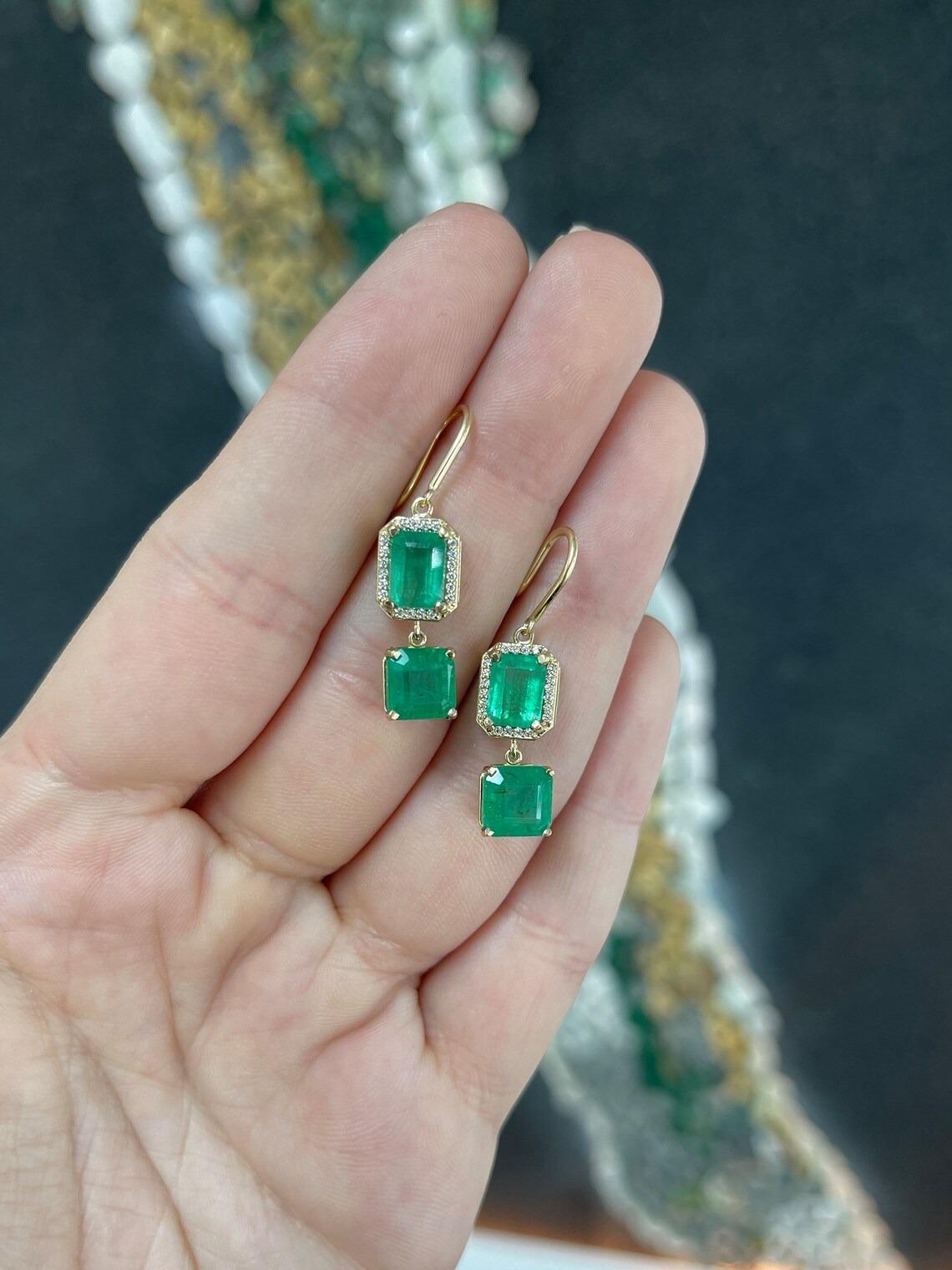 A stunning set of natural emerald and diamond dangle earrings. These spectacular earrings feature over seven carats in emeralds, in both iconic shapes such as the infamous Emerald Cut and Asscher. The gemstones display a remarkable lush green color