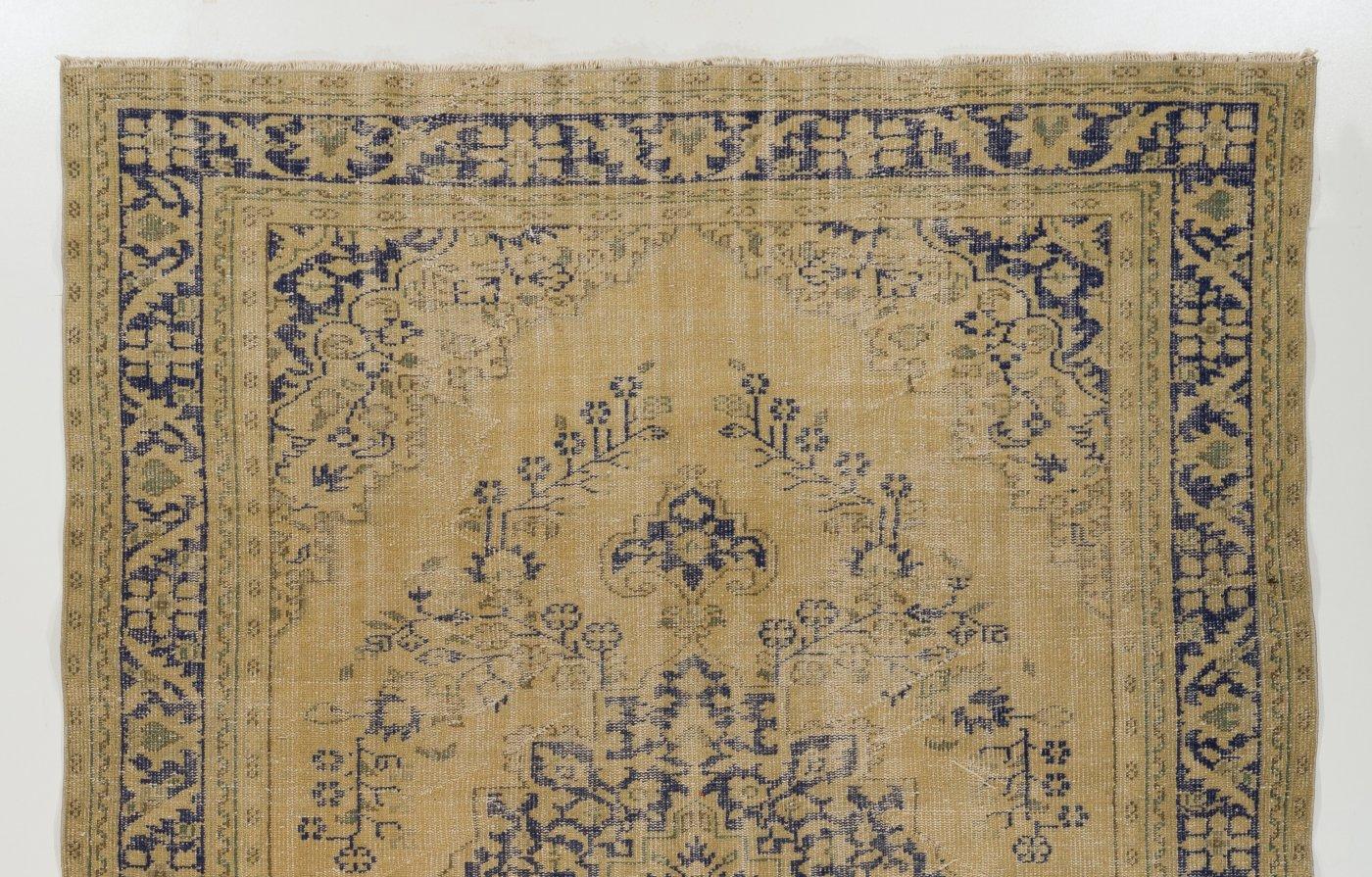 A vintage handmade Turkish Oushak area rug with a delicate central medallion and very-well drawn floral motifs in dark indigo across its beige/sand color natural undyed wool ground. The rug has low wool pile on cotton foundation. It is in very good