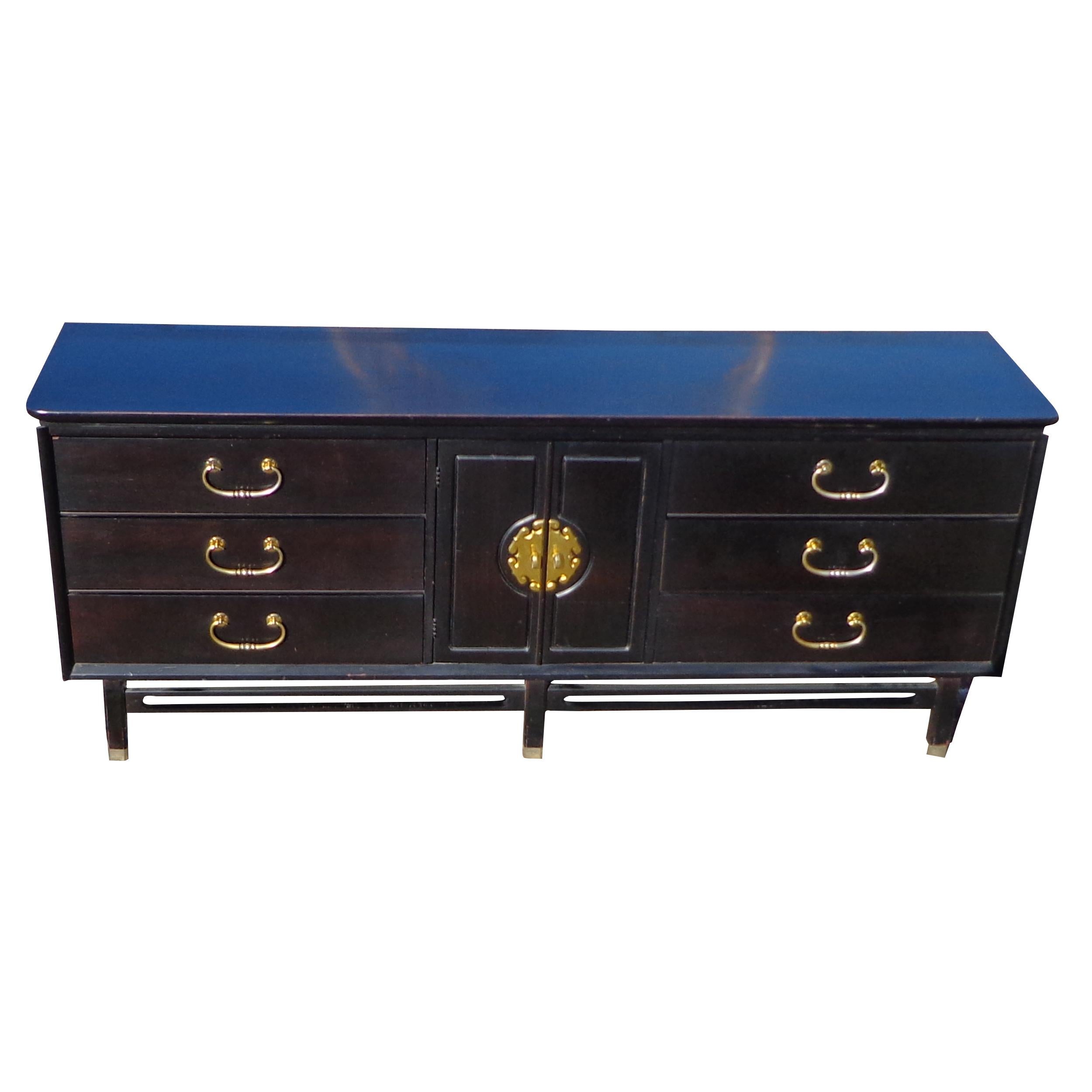 74? Bassett Hollywood Regency style dresser

Hollywood Regency dresser or credenza in an ebony lacquer finish. Features six large storage drawers with brass finished pulls and a two-door storage area with a brass medallion.