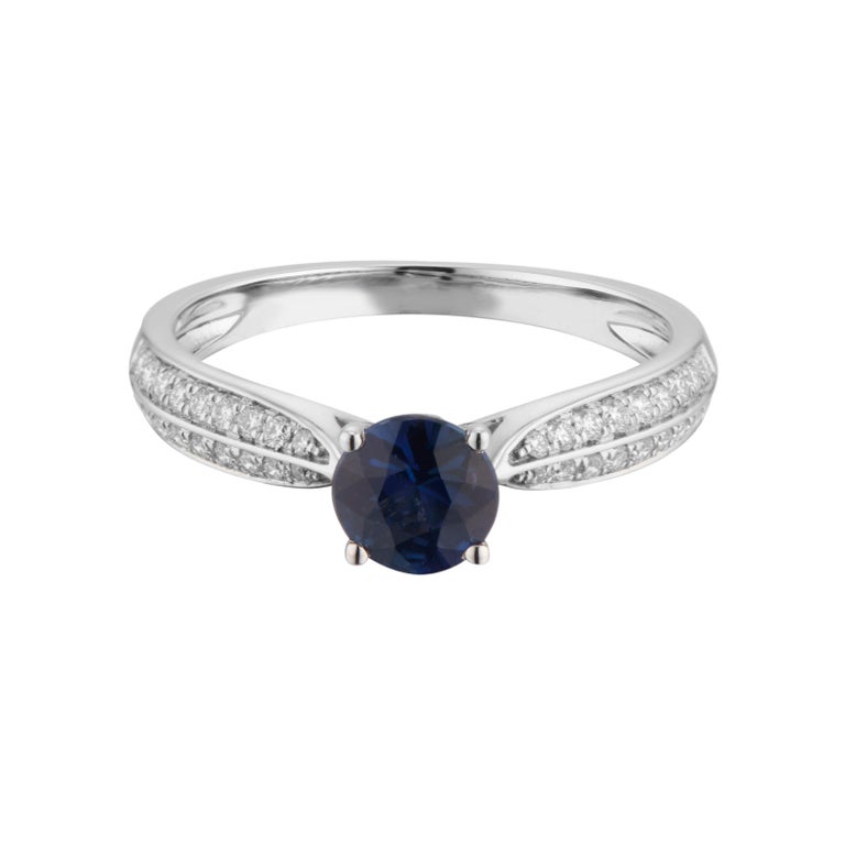 Sapphire and diamond engagement ring. Round blue sapphire center stone in a 14k white gold setting with 38 around accent diamonds along both sides of the shank. 

1 blue sapphire, approx. .74cts
38 diamonds, G VS-SI approx. .23cts
Size 7 and