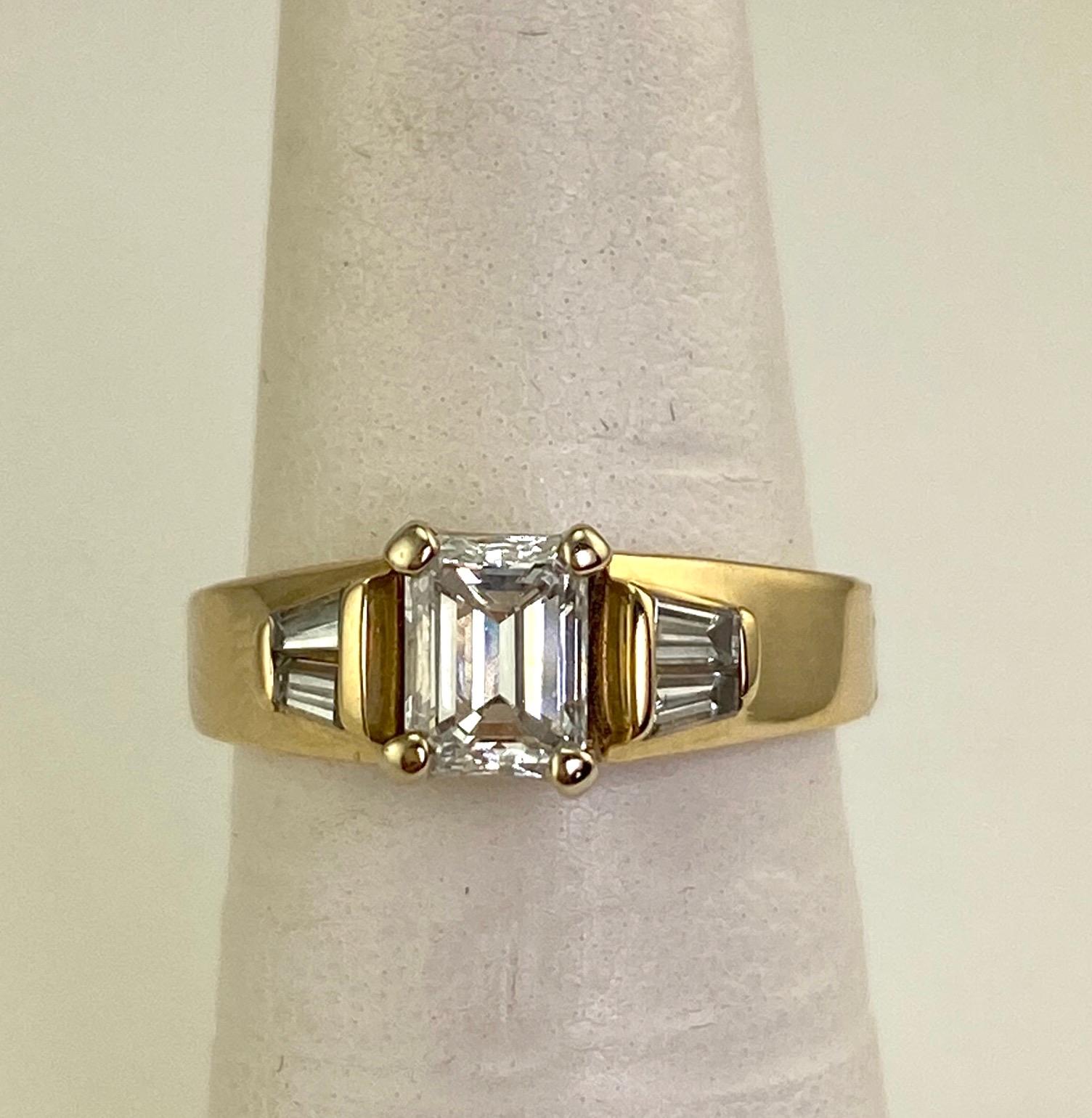 Natural emerald cut diamond weighing approximately .74 carat. The clarity is VVS2. The color is G-H. The conservative grading was performed by a GIA Graduate Gemologist. The baguette side diamonds weigh approximately .26 carat total. The 14 karat