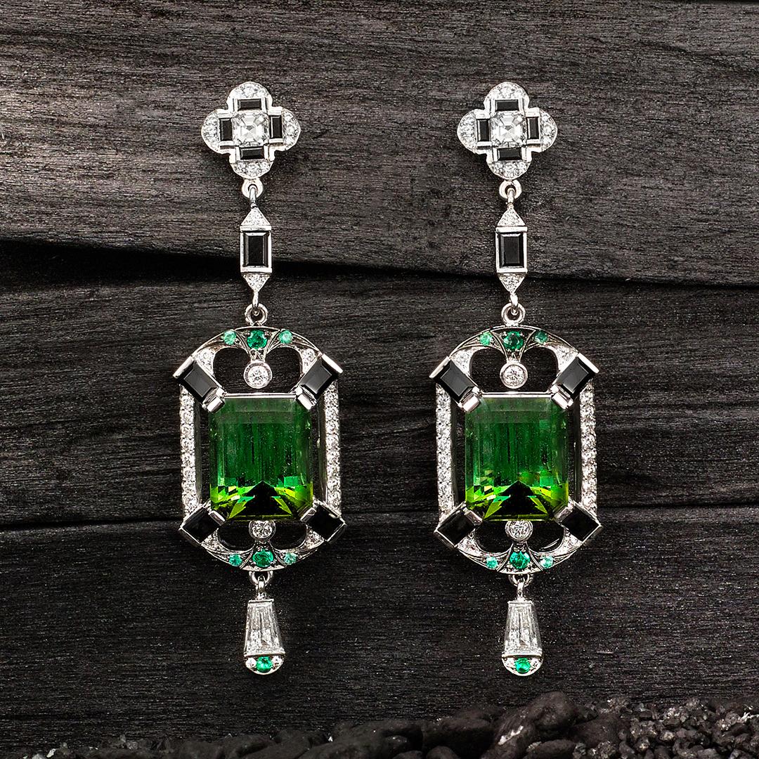 These Matthew Ely 18ct White Gold Art Deco style drop earrings are set with two emerald cut Green Tourmalines equalling 7.44ct, framed by Black Spinel Baguettes, white diamond tapers equalling 0.26ct and tiny emeralds. Let us source a special