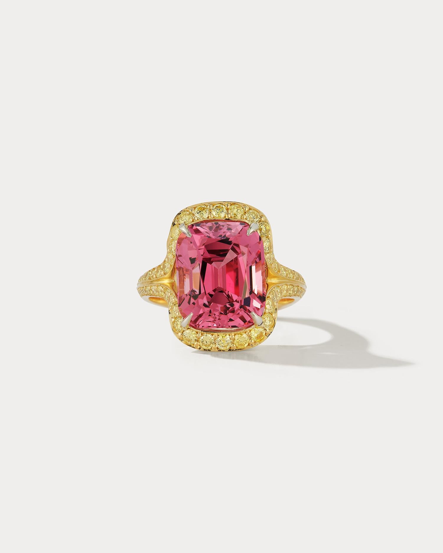 Introducing a breathtaking piece of jewelry: a 7.49 carat cushion cut peachy pink spinel surrounded by .94 carats of intense yellow diamonds, set in 18k yellow gold. The warm and vibrant combination of the pink spinel and yellow diamonds creates a