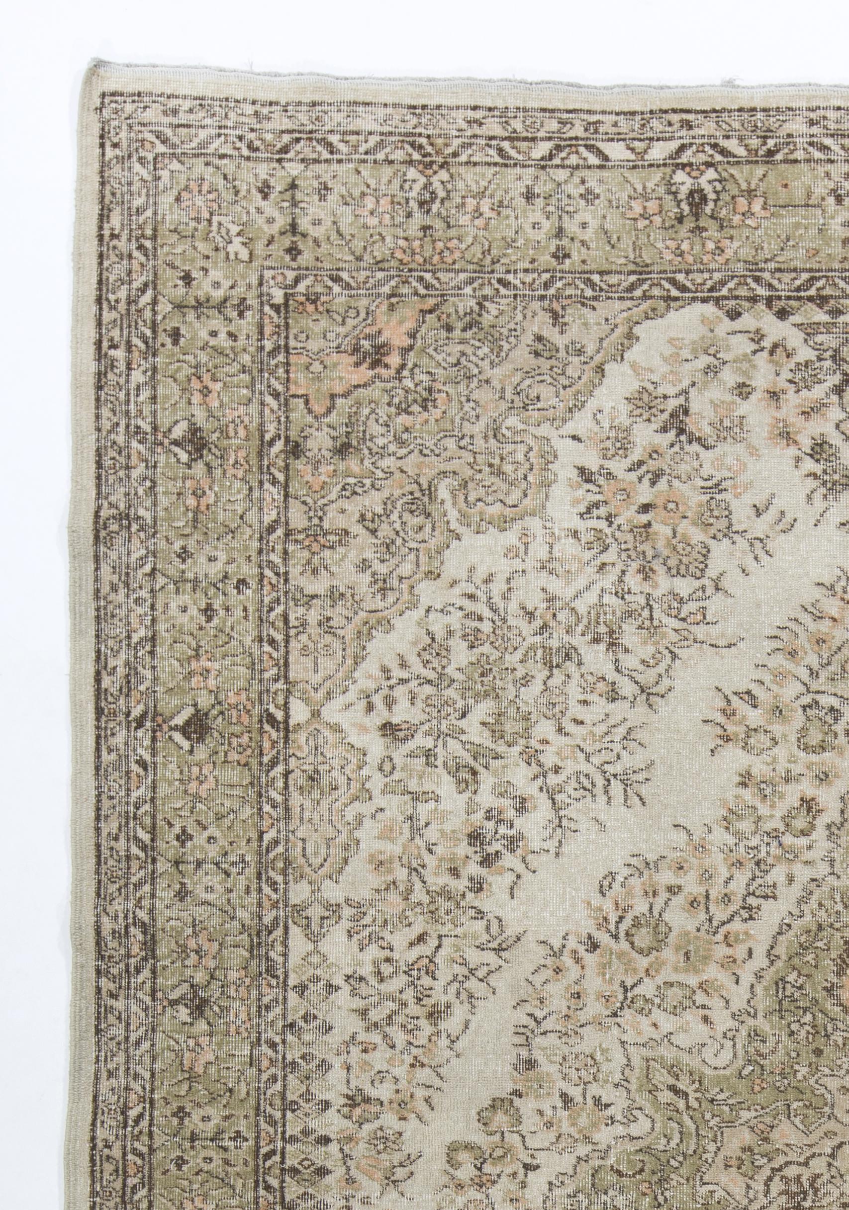 A finely hand-knotted mid-20th century area rug from Western Turkey in soft and earthy colors of light coral pink, ivory, light moss green and brown, featuring a central medallion decorated all around with intricate dainty florals. The rug has low