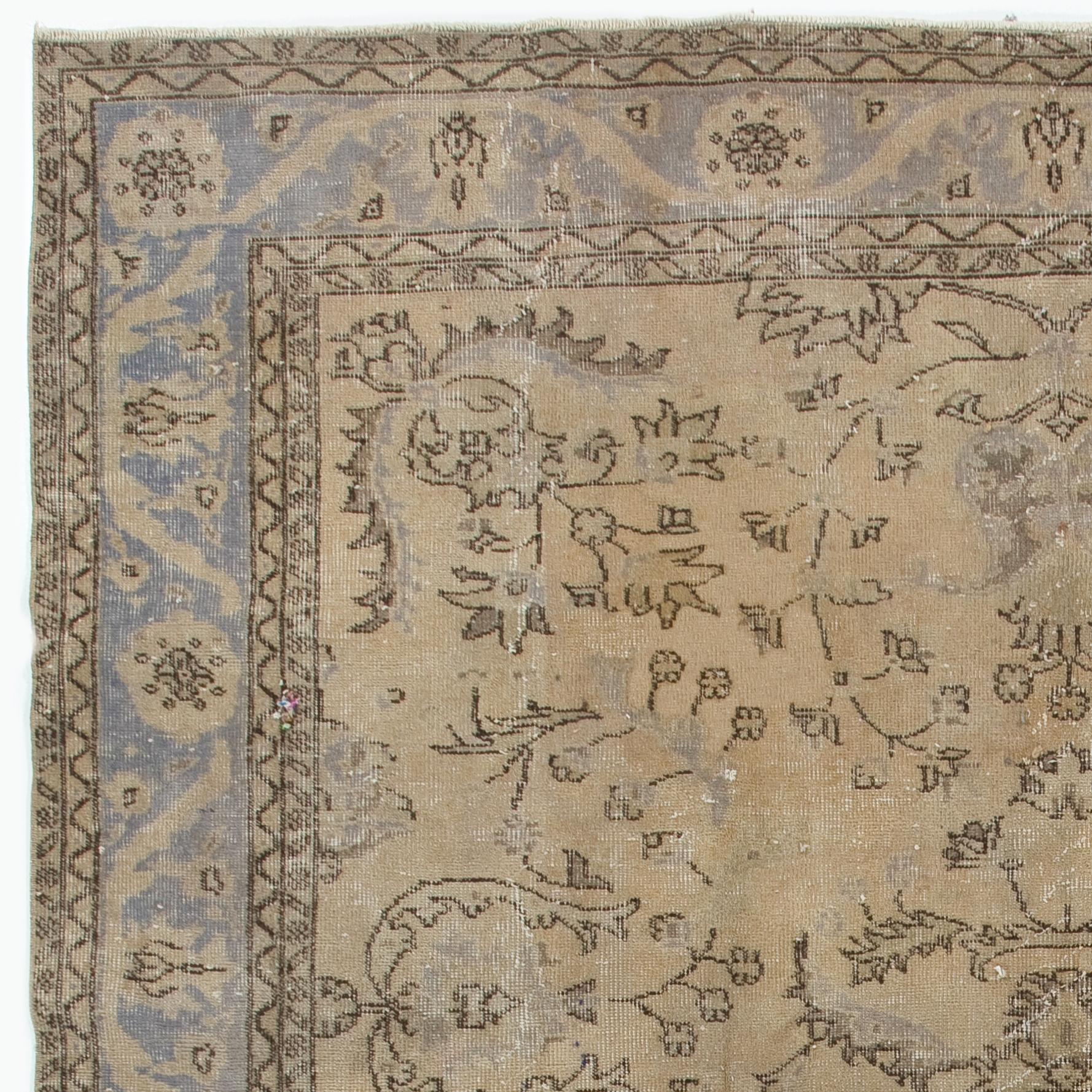 A vintage hand knotted Turkish Oushak rug in a very soft, muted palette of beige, khaki, ecru, tan, fawn and dark steel blue. The rug features two floral medallions at both ends of the field that is filled with symmetrically placed floral vines