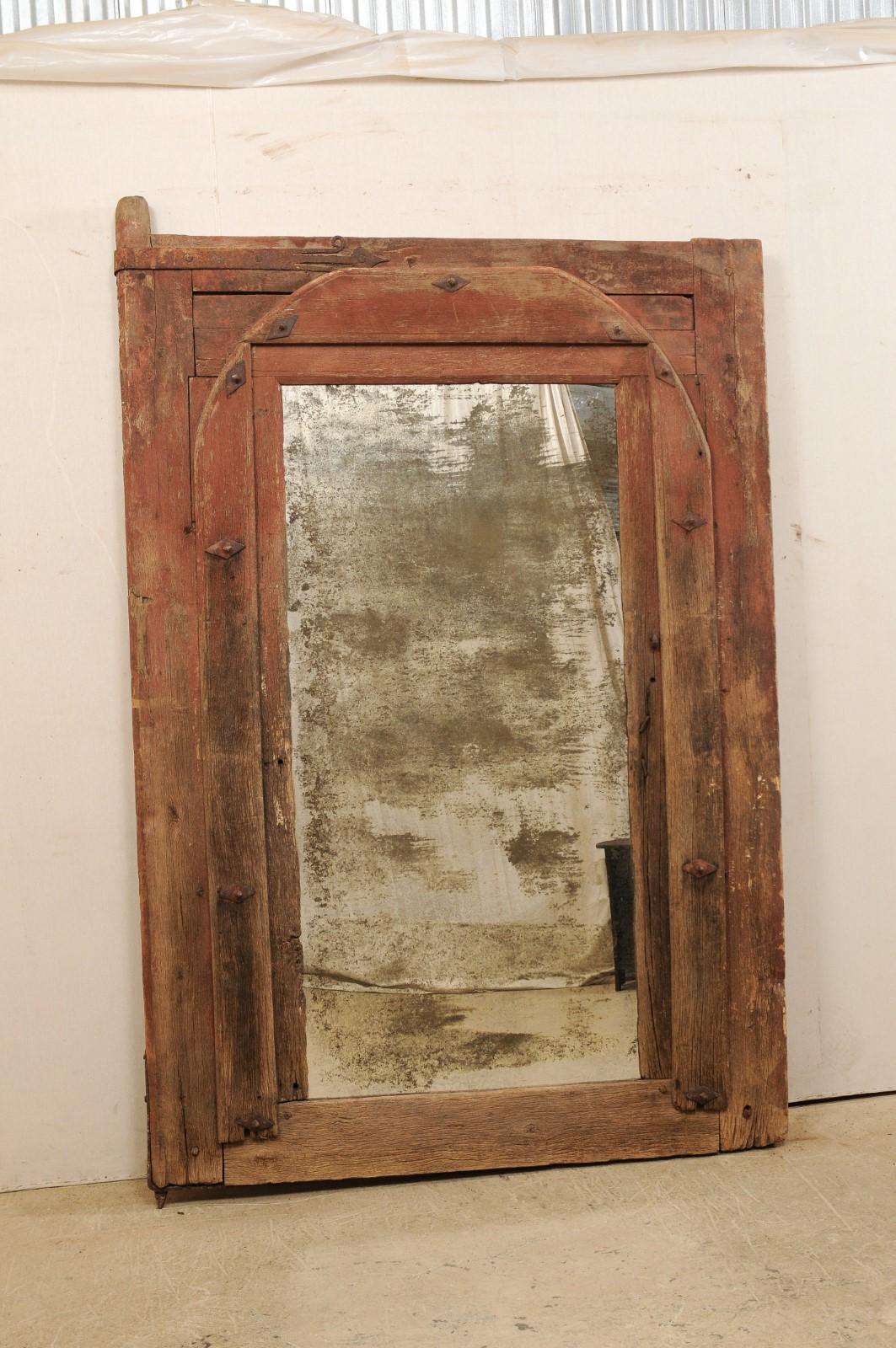 A one of a kind custom mirror using an 18th century Spanish door frame as surround. This antique wooden door frame from Spain acts as the surround for this custom designed mirror which stands impressively at over 7.5 feet in height. The door retains