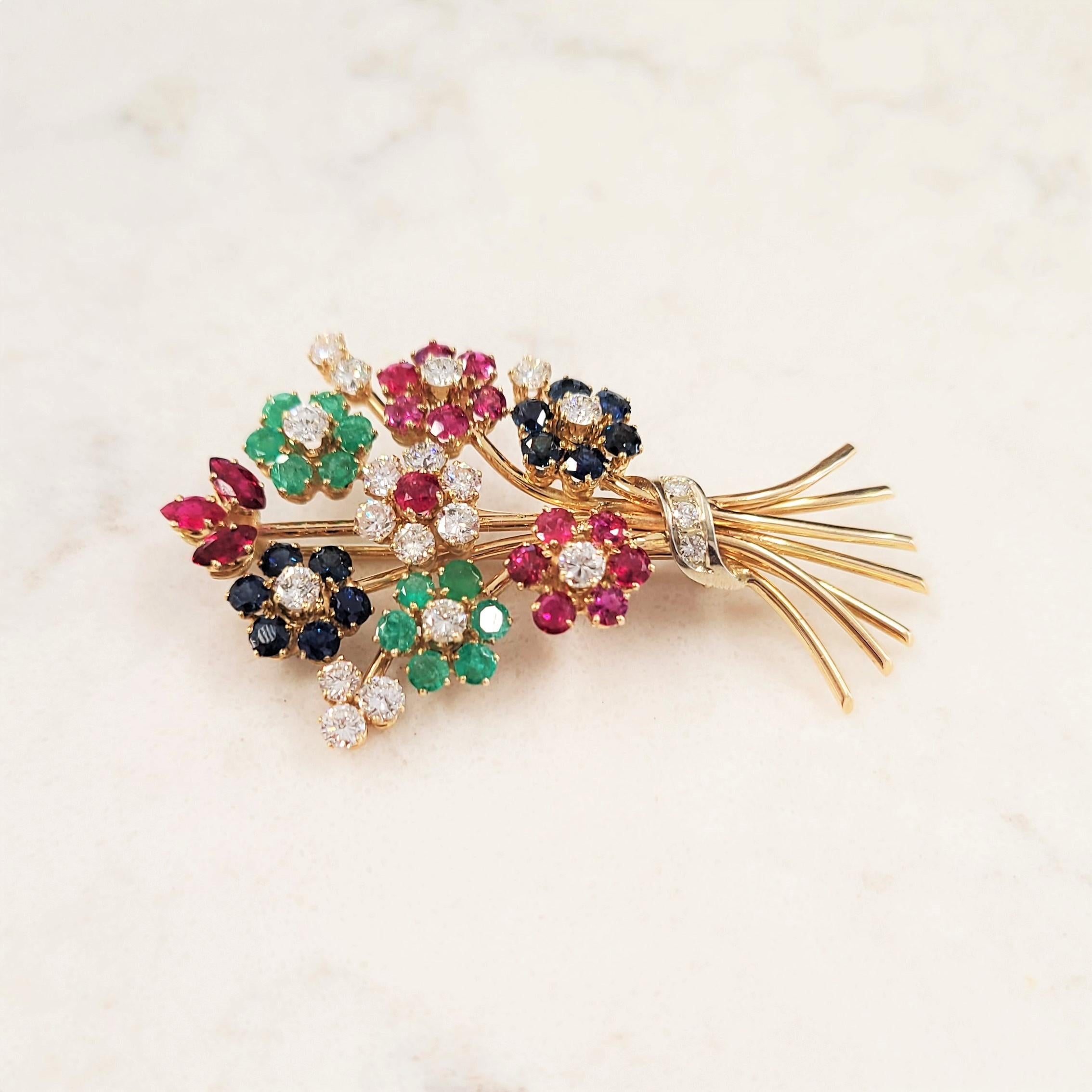 This precious gemstone bouquet showcases a bonanza of color and luxury! This brightly polished 14k white gold bouquet features rubies, diamonds, sapphires, and emeralds mixed into bunches of flowers and leaves in a vibrant cascade of brilliance and