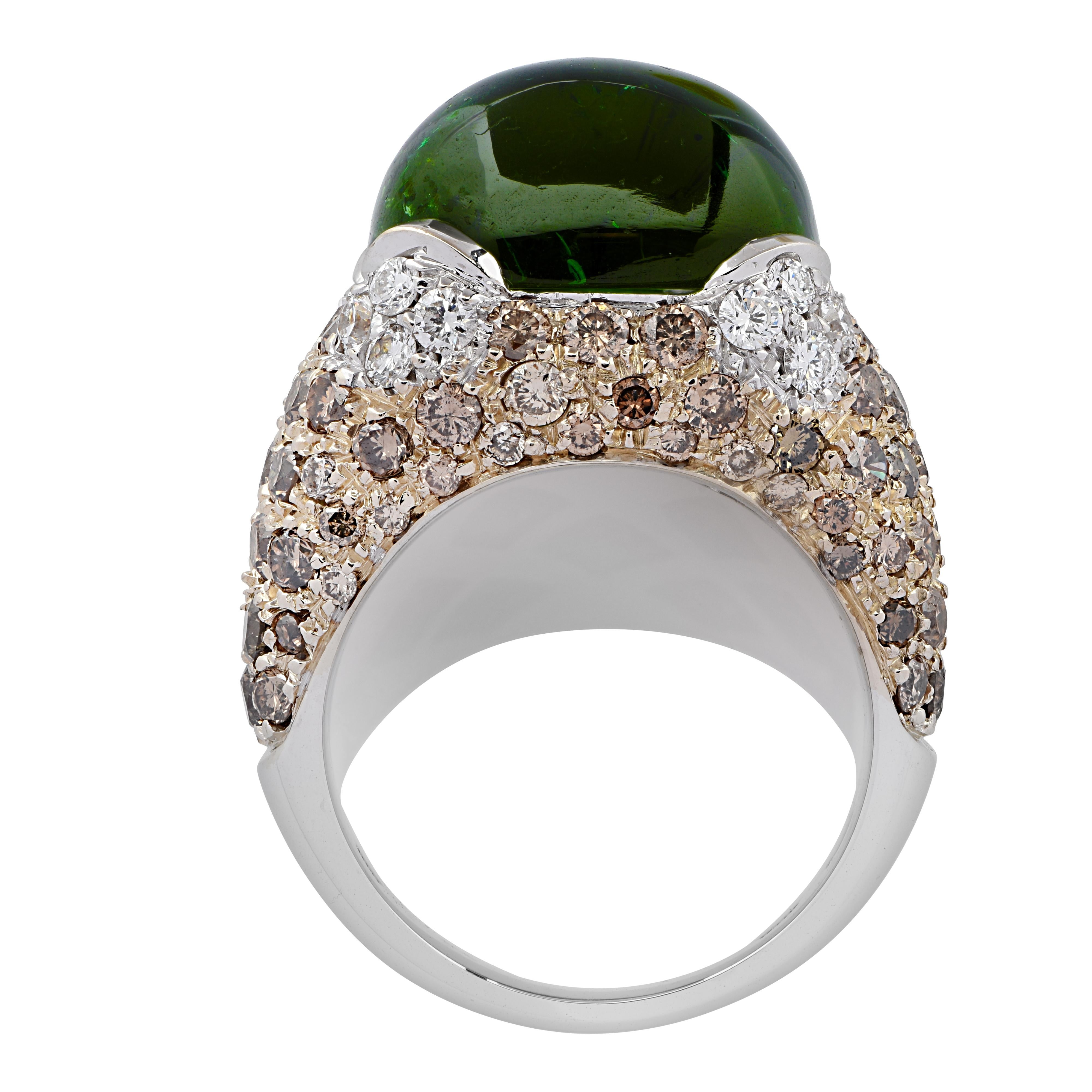 Spectacular ring crafted in white and yellow gold showcasing a gorgeous cabochon cut green Tourmaline accented by approximately .90 carats of round brilliant cut brown diamonds, and G color diamonds, VS clarity. The Tourmaline rests on a bed of