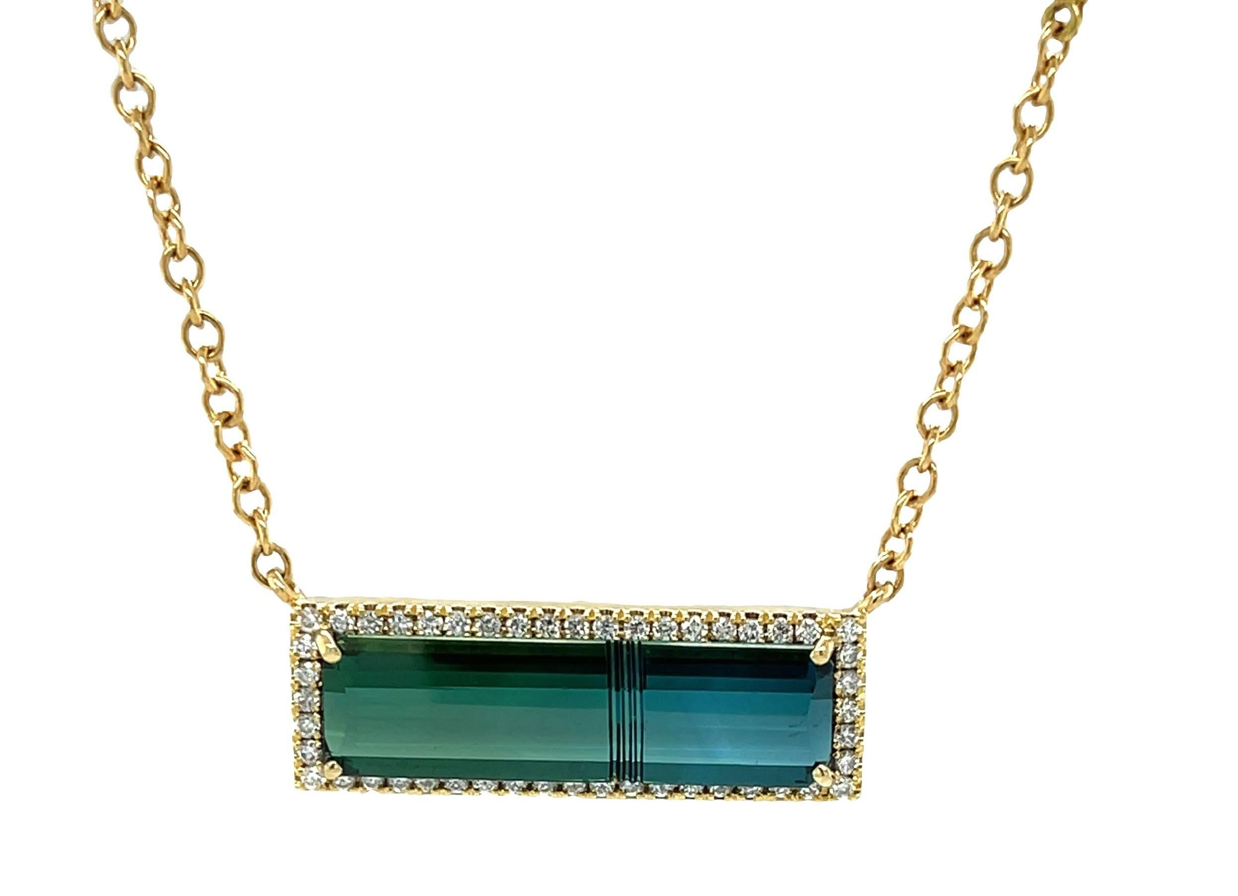 The beautiful elongated shape of this indicolite tourmaline displays an uncharacteristic bicolor blend of teal and green.  It is a custom cut piece that is carved on the intersection of the two colors it displays. This sleek gem is showcased in a