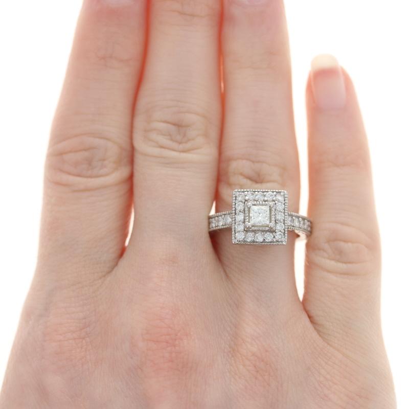 Propose to your love with the ring of her dreams! Featuring a square halo design, this 14k white gold engagement piece showcases a princess cut diamond solitaire accompanied by round brilliant cut diamond accents highlighted by ornate milgrain work