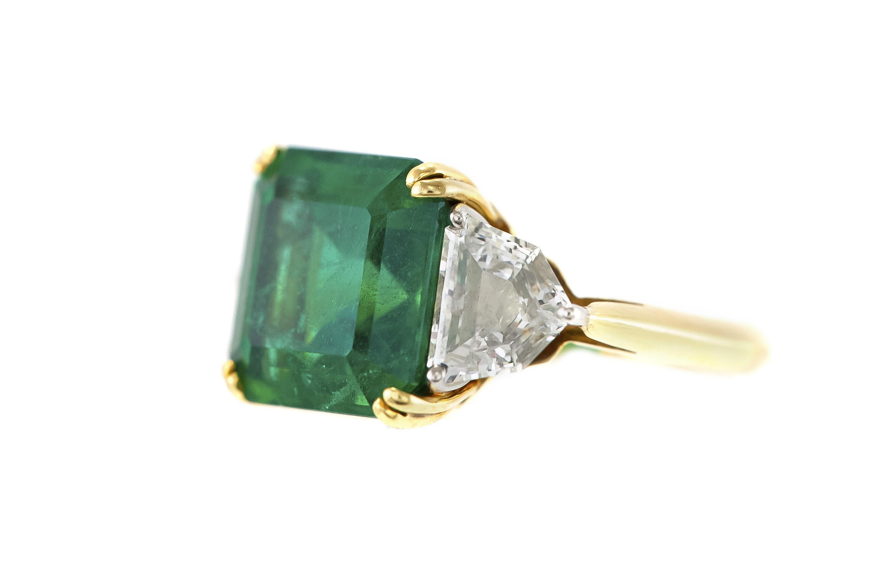Finely crafted in 18K yellow gold with an AGTA certified Zambian Emerald weighing 7.60 carats and a pair of accenting Shield cut side Diamonds weighing a total of approximately 1.30 carats. 
Size 5 3/4, resizable