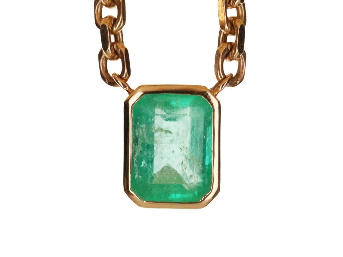 A spectacular unisex emerald solitaire necklace. The featured stone is 7.61-carats, emerald cut. The emerald has a beautiful medium green color, with very good luster and minor imperfections. This large beauty is set in a bezel-set, 14K yellow gold