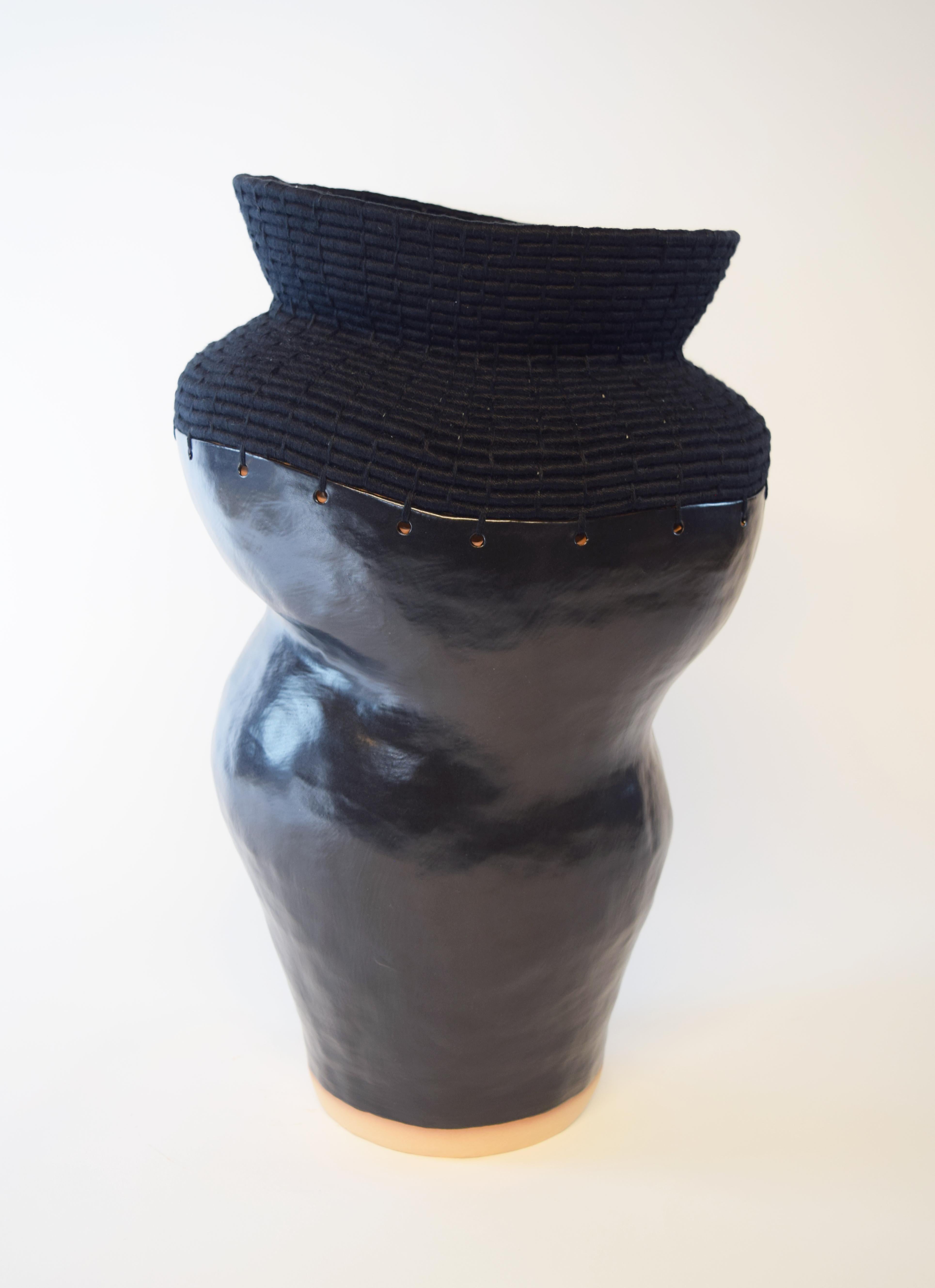 762 Black vessel by Karen Gayle Tinney
Dimensions: D 25.5 x W 25.5 x H 46 cm 
Material: Stoneware with cream, shino glaze, Black cotton.

Karen Gayle Tinney is an artist and designer whose work consists of pieces that combine ceramic and fiber,