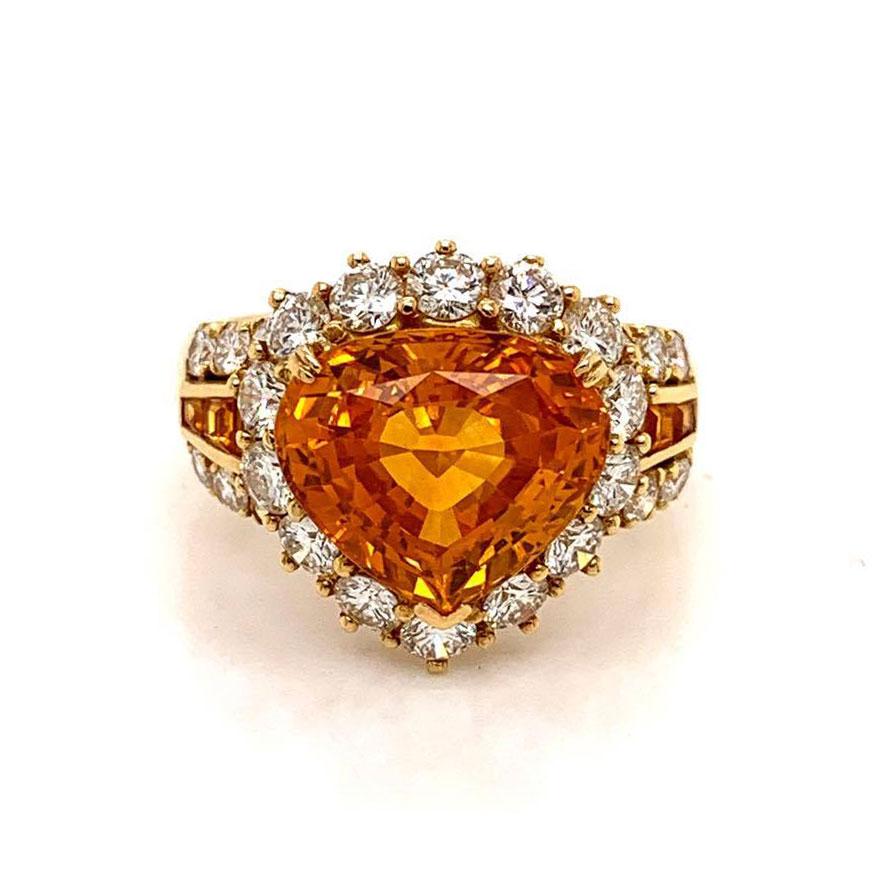 A luscious gem ring featuring a 7.66 carat fancy orange sapphire. The sapphire has a bright vivid color and is free of any inclusions allowing for its great brilliance to be showcased. It is accented by 1.75 carats of round brilliant cut diamonds
