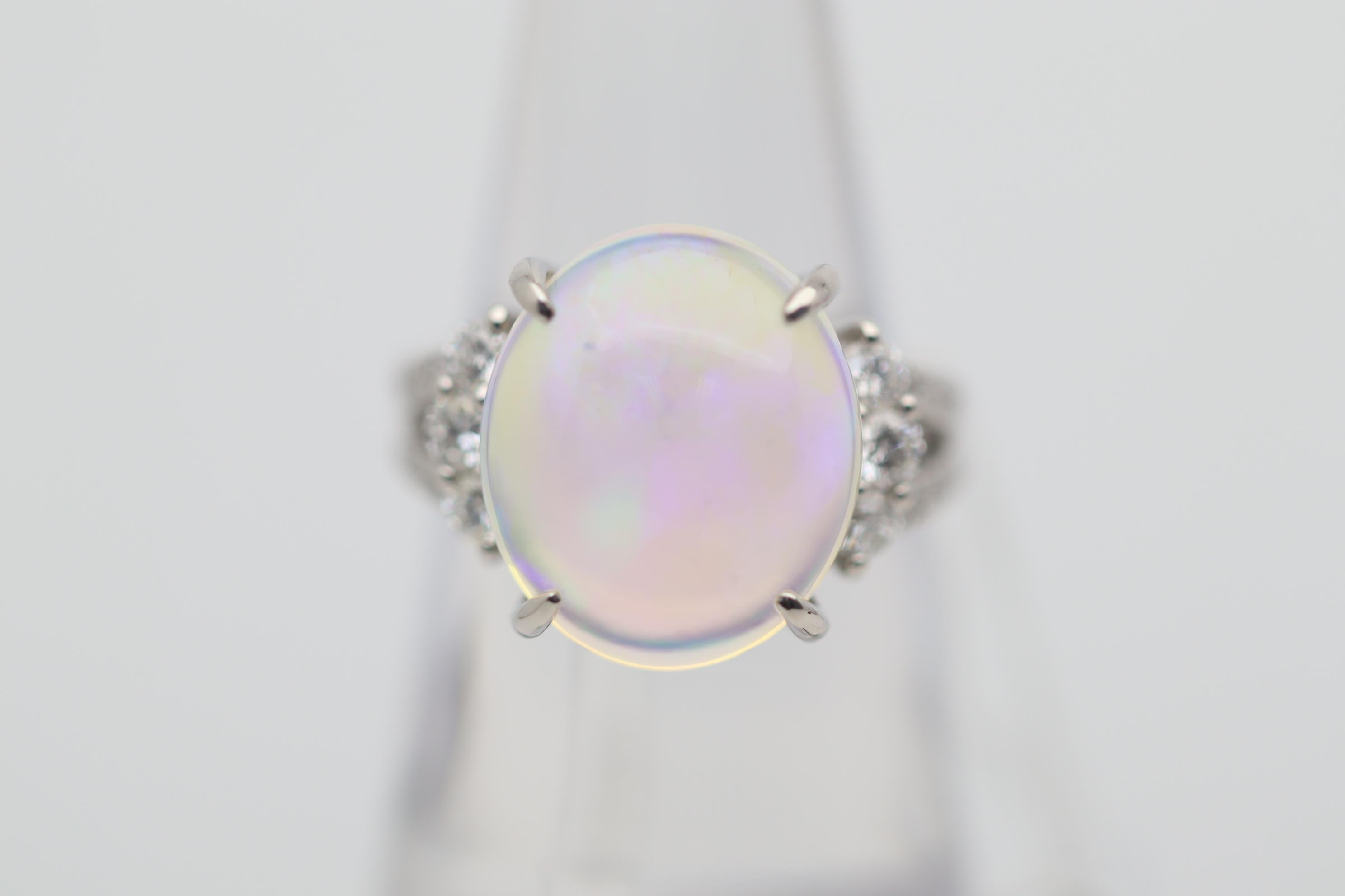A lovely platinum made ring featuring a fine Australian crystal opal weighing an impressive 7.67 carats. It has strong play-of-color as bright intense flashes of blue, green, purple and some reds dance across the crystal clean opal. It is accented