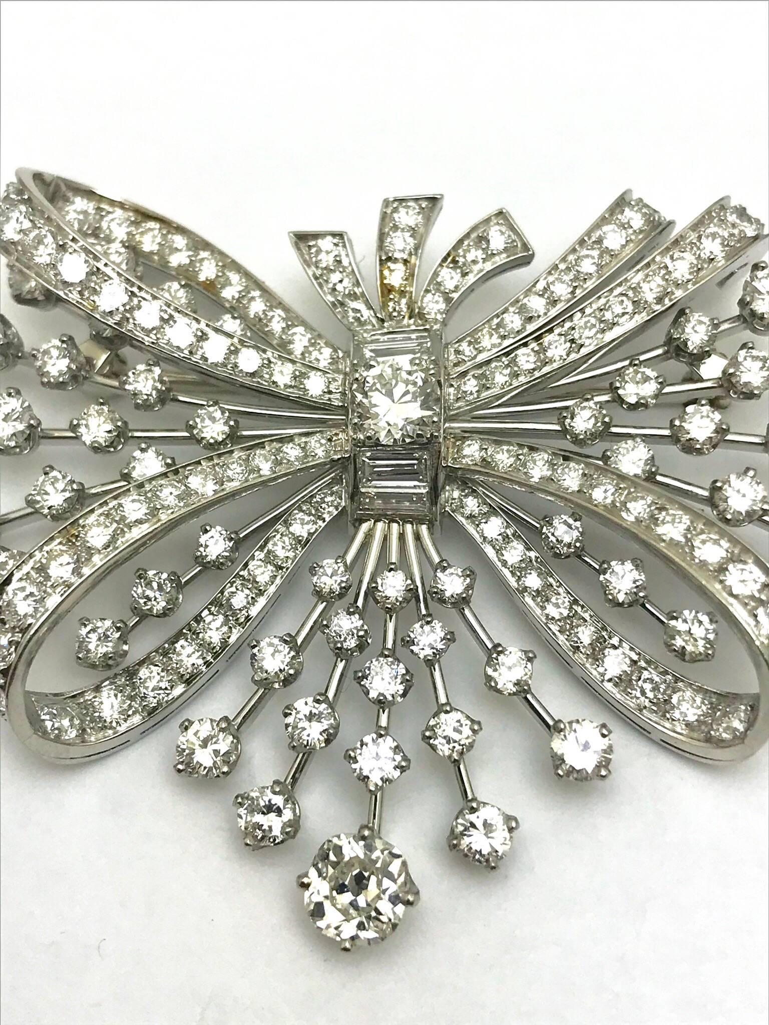 A 7.67 carats round and baguette diamond platinum spray bow brooch.  The bow has diamonds set throughout, and the spray has diamond spaced out on stems of platinum.  There are 151 round diamonds and four baguette diamonds, graded as G-I color, VS