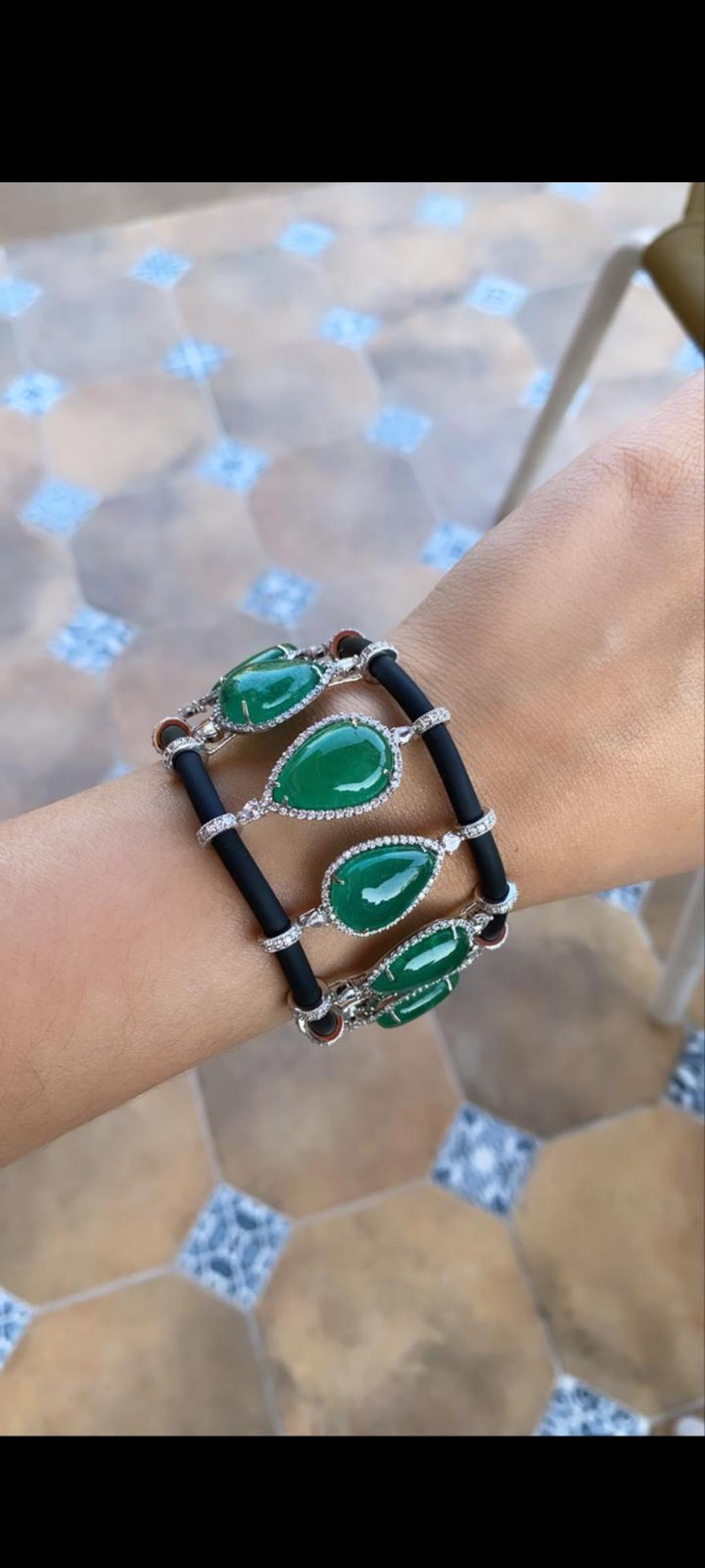 A modern and chic natural emerald and diamond bracelet set in 18k white gold on a leather/rubber chord. The emerald is natural and weight is 76.73 carats with 4.82 carats diamond weight . The net gold weight is 36.455 grams and bracelet dimensions
