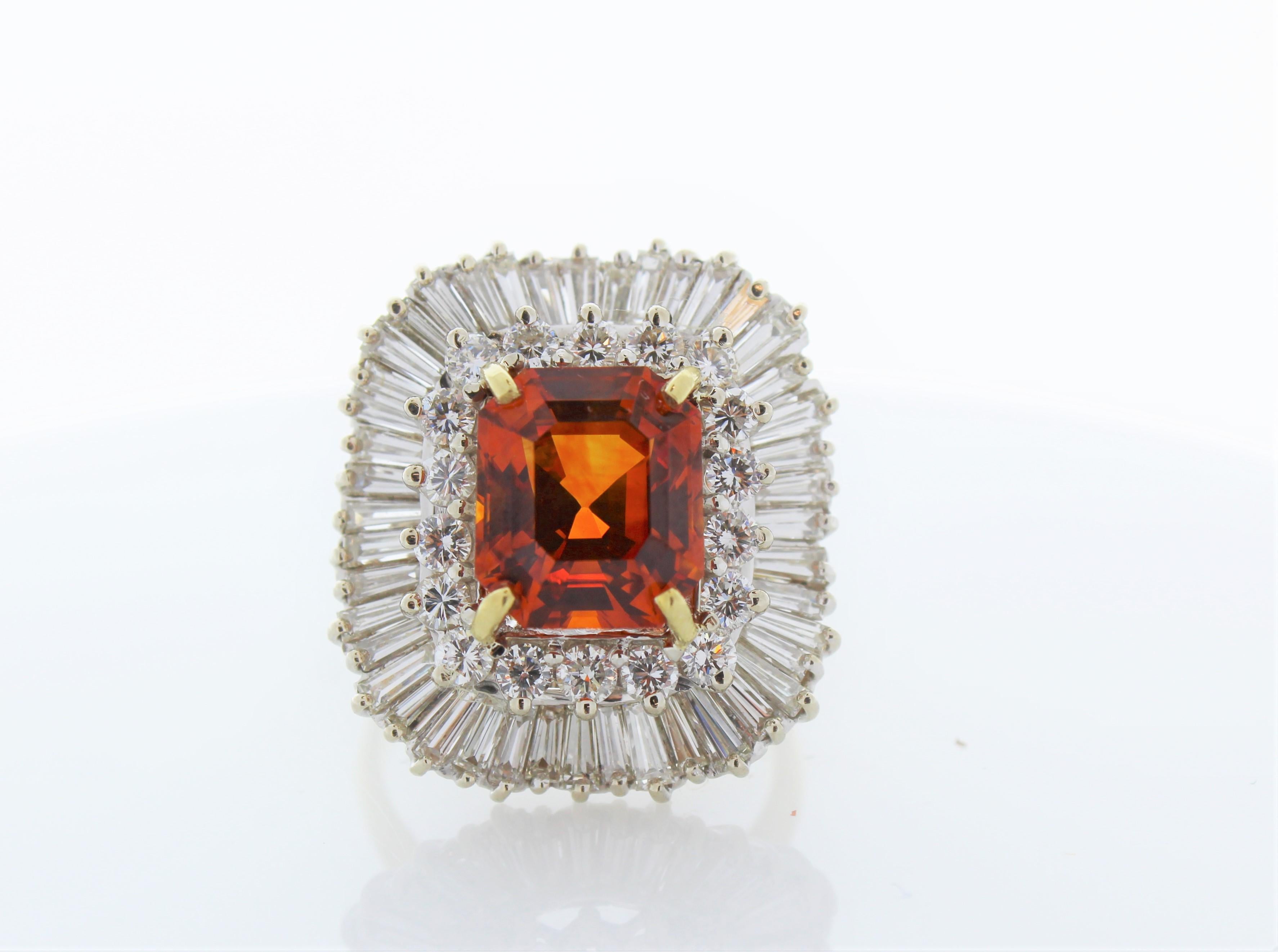 The 7.70 Carat Emerald Cut Orange Sapphire and Diamond Ring in 18K White Gold is a truly exquisite and captivating piece of fine jewelry that beautifully combines the richness of a rare orange sapphire with the timeless elegance of white gold and