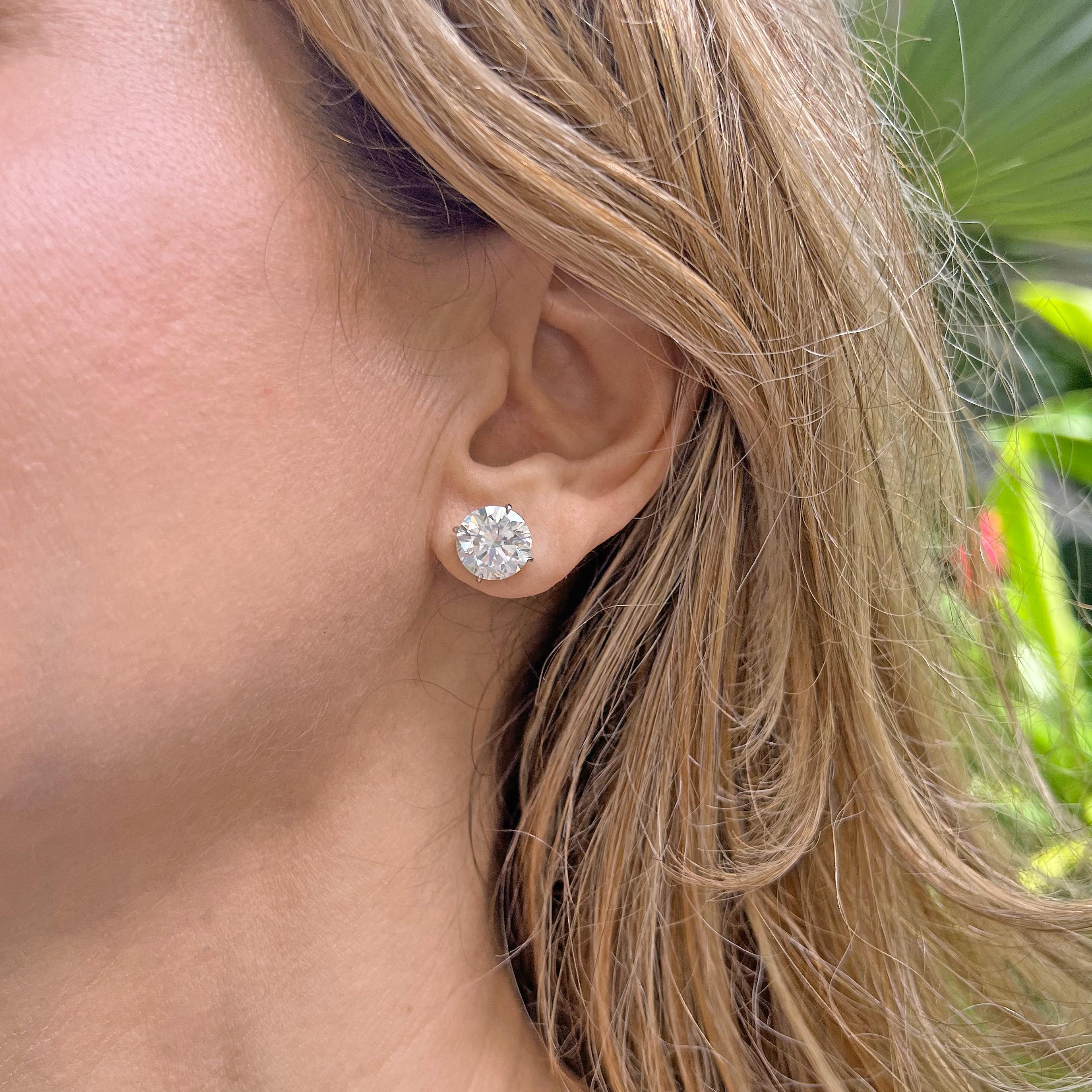 Round brilliant cut diamond stud earrings, showcasing a pair of well-matched near-colorless diamonds weighing 7.70 total carats, the diamonds secured in four-prong platinum martini settings with posts for pierced ears. Both diamonds are J-color and