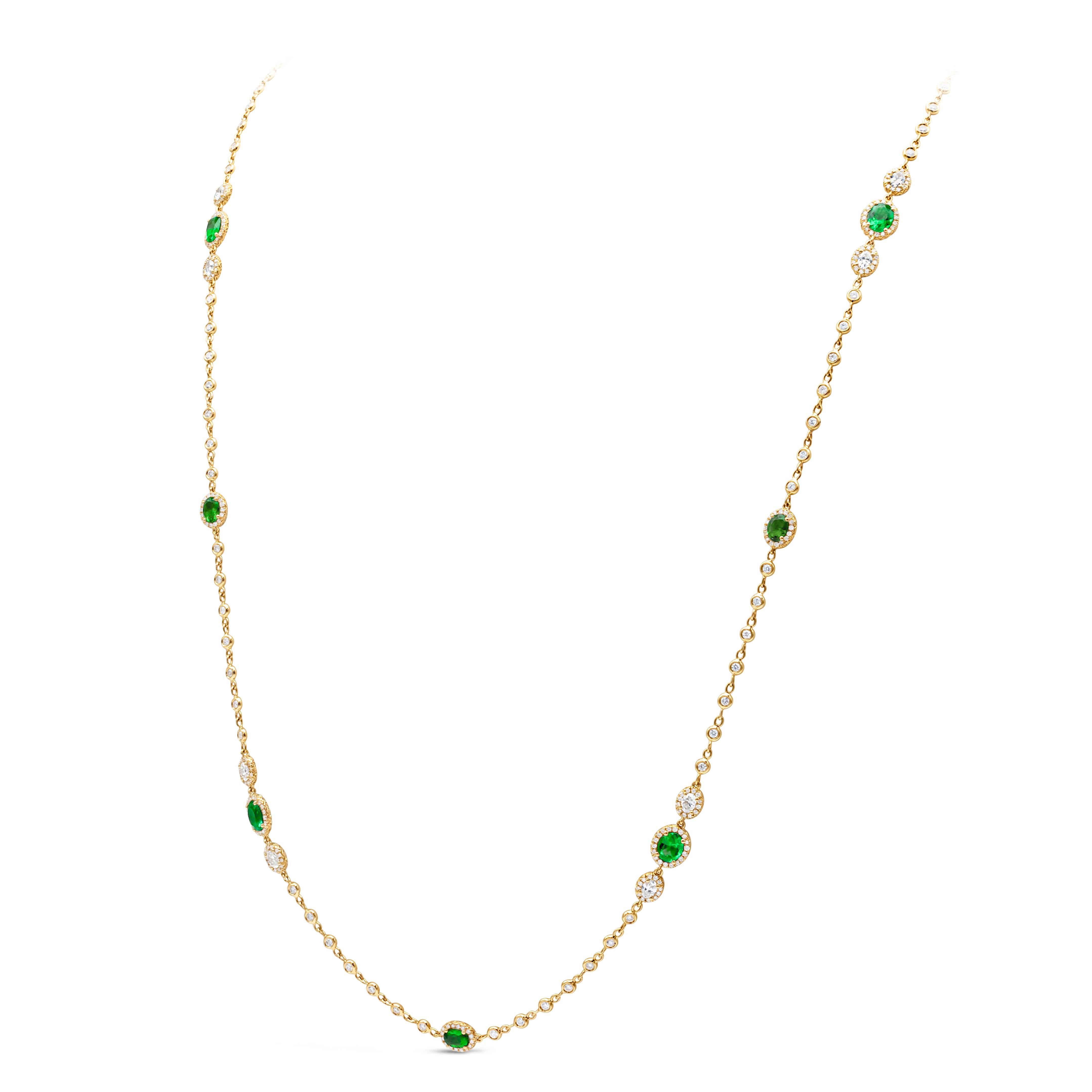 A fashionable and attractive diamond by the yard necklace showcasing an oval cut Colombian green emerald and brilliant round diamonds, set in a row of round brilliant diamonds in a halo design. Each diamond halo is evenly spaced with more bezel set