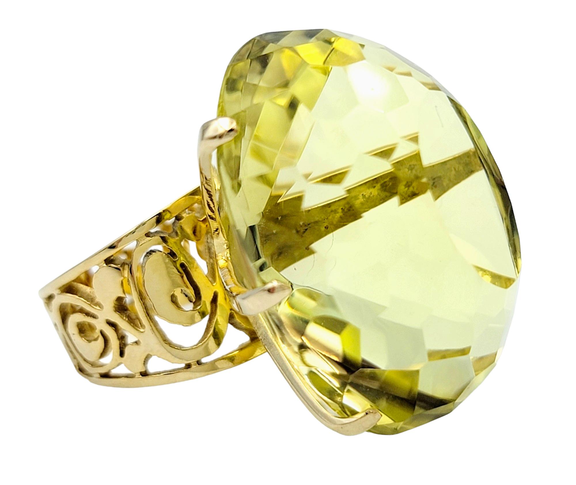 Ring Size: 5.5

This massive high profile citrine ring is a true statement of opulence and bold elegance. A majestic oval-cut citrine, boasting a substantial weight of just over 77 carats, commands attention with its light yellow-greenish hue,