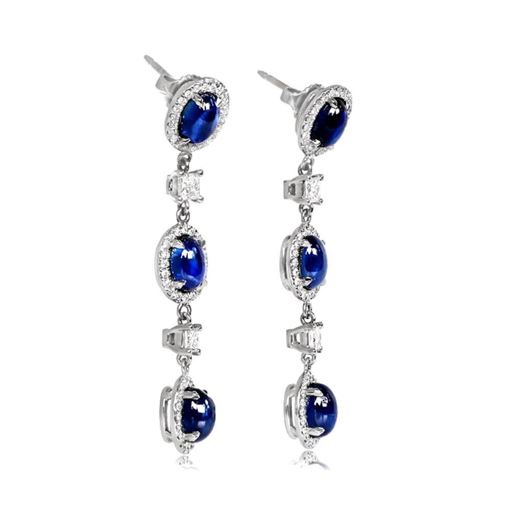 Exuding elegance and luxury, these exquisite hanging earrings are meticulously handcrafted in 18k white gold. 

Each earring showcases a trio of mesmerizing cabochon cut sapphires, surrounded by halos of dazzling round brilliant diamonds. Between