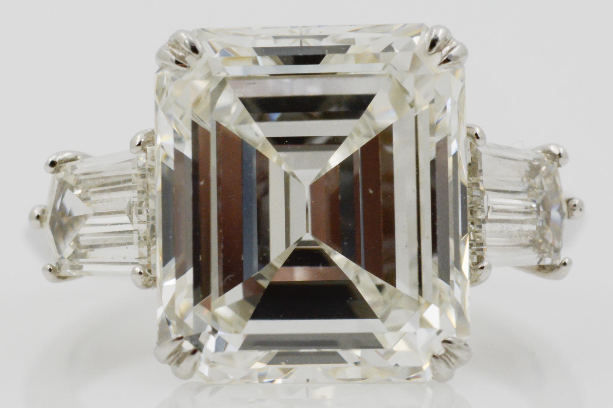 At the center of this platinum GIA certified diamond ring is an approximately 7.71 carat emerald cut diamond with I color and VS1 clarity. It is paired with two shield cut diamonds weighing approximately 1.20 carats, GH color, and VS clarity. The