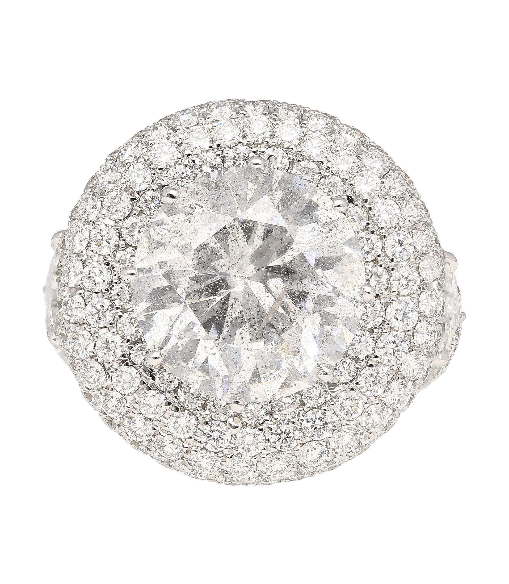 7.71 carat round cut natural diamond cluster ring in 18k white gold with 4.98 carats in white pave set diamonds.

The ring is further adorned with two Trillion-cut Diamonds (0.58CTTW) on the sides, adding a touch of sophistication. Additionally, 291