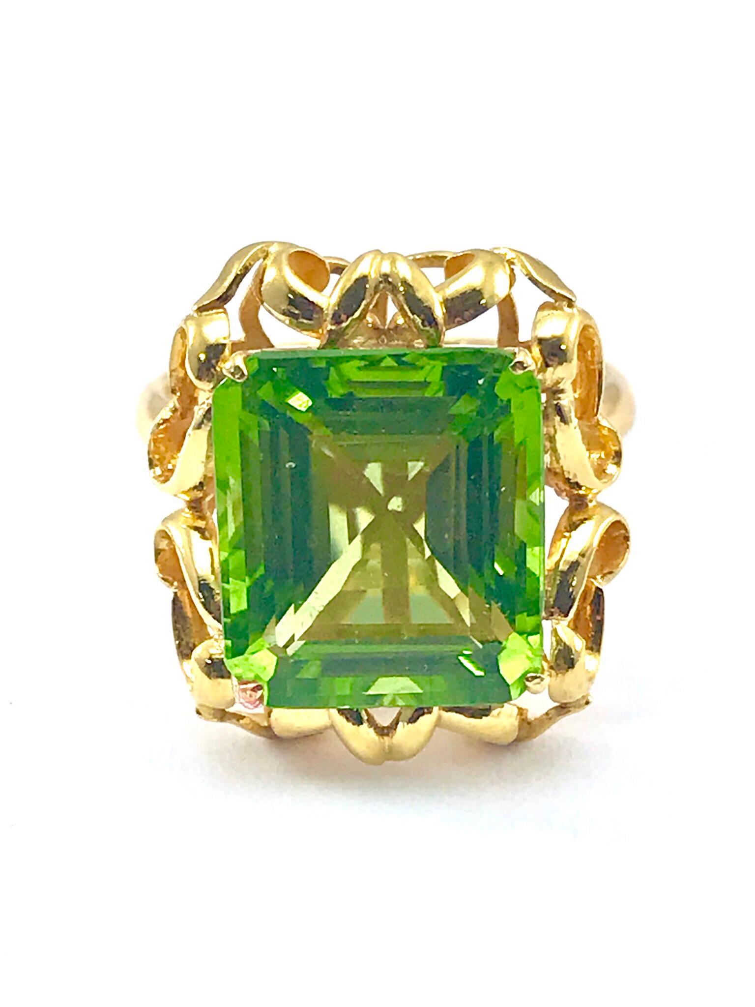 A stunning 7.71 carat step cut lime green Peridot and 18 karat yellow gold cocktail ring.  The Peridot is set with four prongs in an abstract deigned mounting, and a rounded edge shank.  This is a great ring to wear to any occasion, and it is