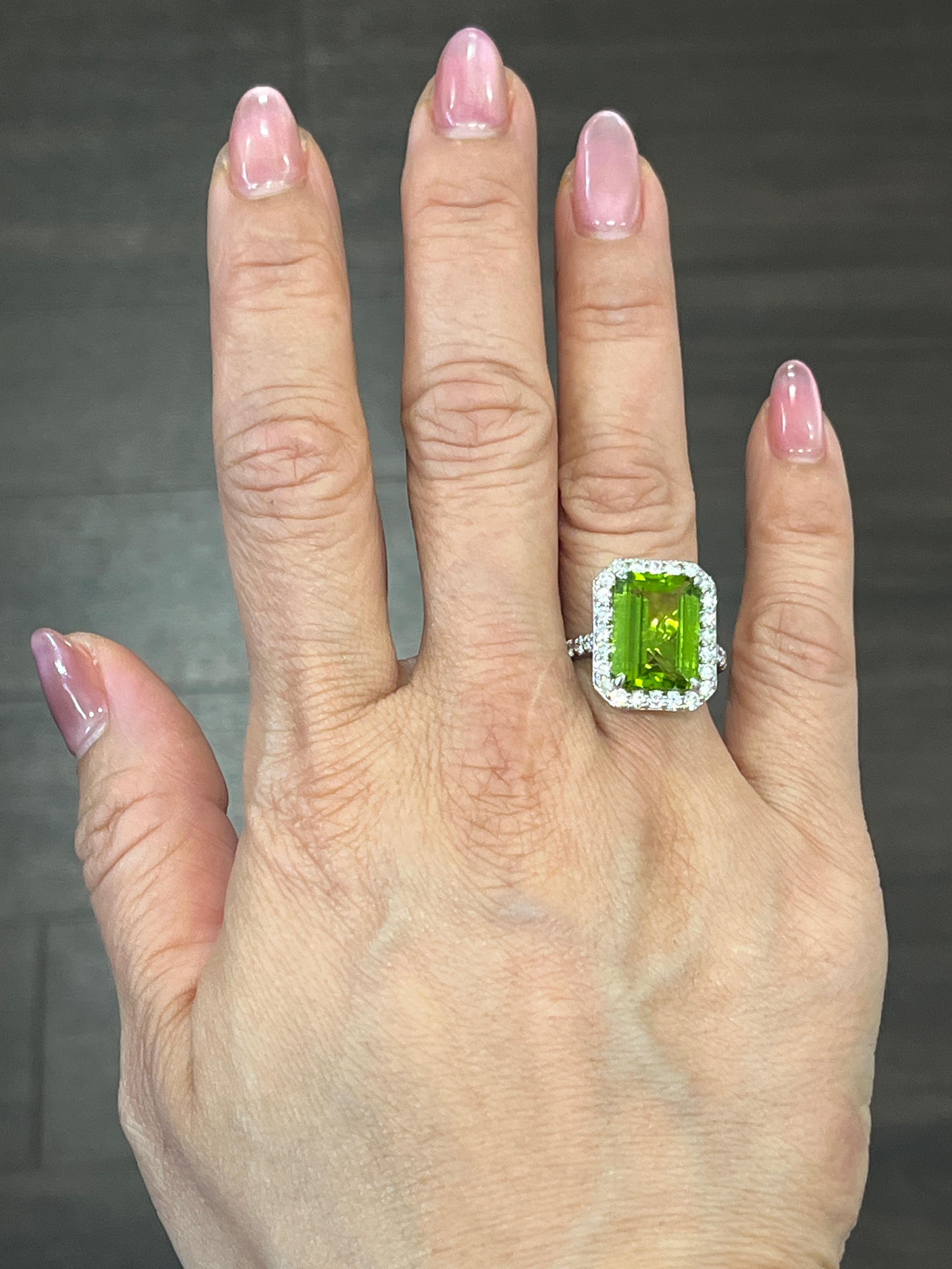 This gorgeous 18k white gold ring is set with an emerald cut natural green peridot weighing 6.67 ct. The emerald cut natural green peridot is surrounded with 36 round diamonds with a carat weight of 1.06. The diamonds boast a color of F/G and a