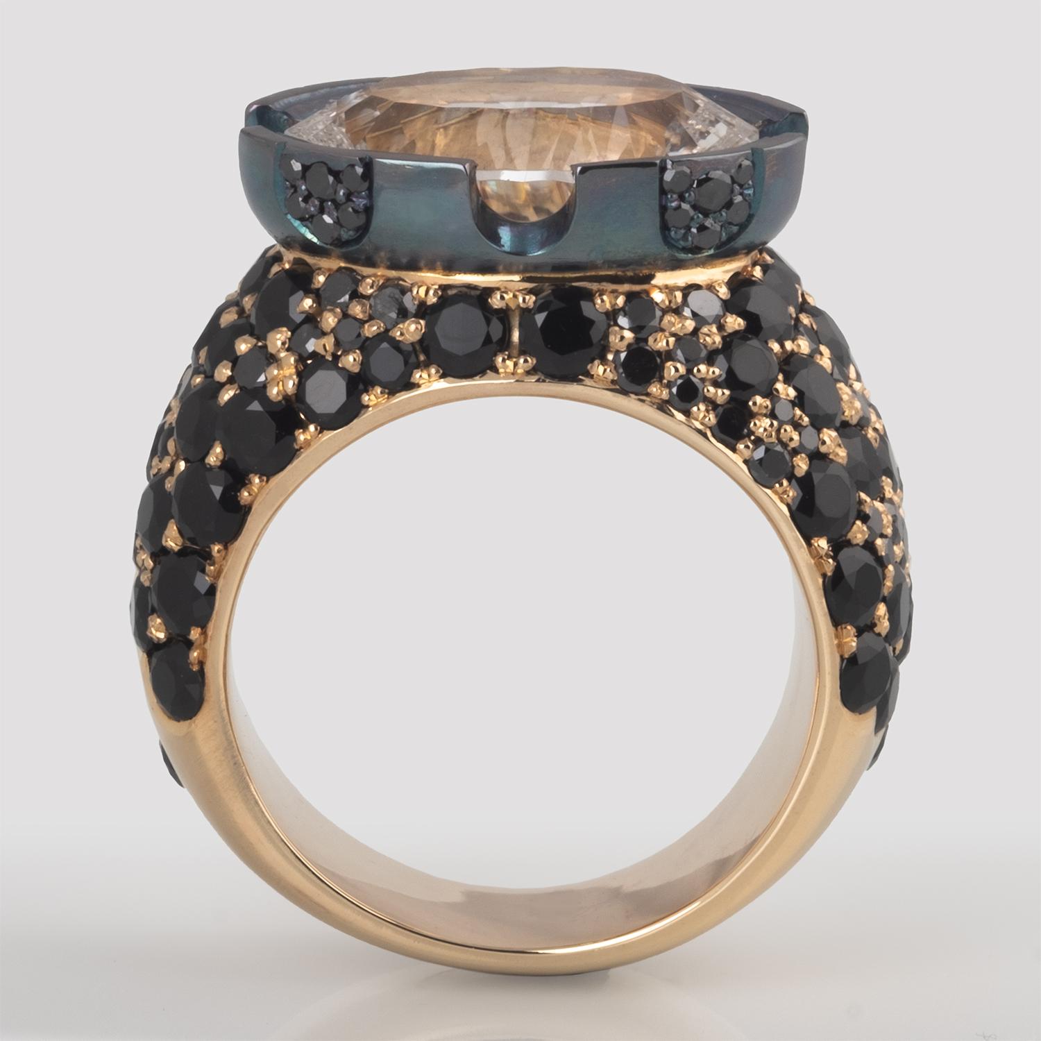 The unique cut of the 7.74 carat oval White Quartz gemstone was the inspiration for this one of a kind ring. A mix of black Diamonds and black Spinels surround the blackened sterling silver bezel. The bezel features cutouts that echo the concave