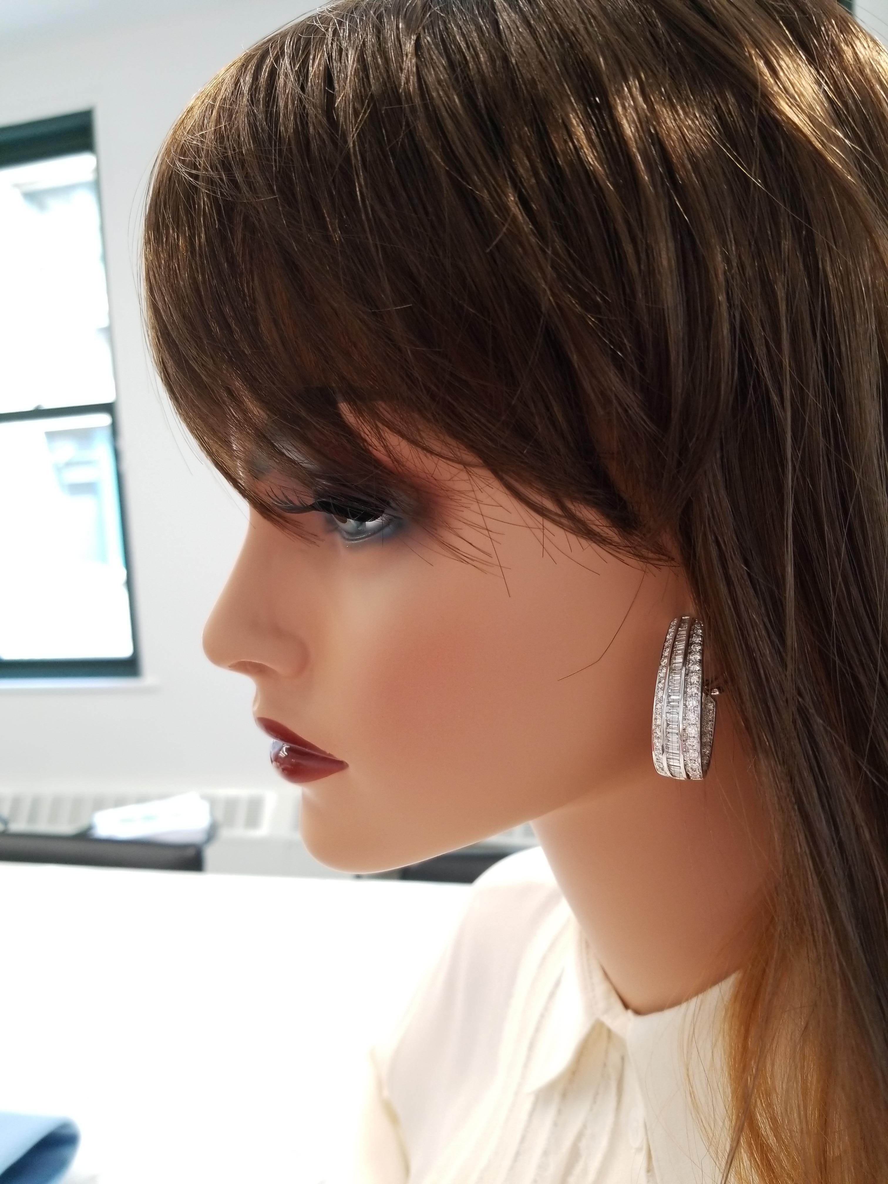 These are fancy J-shaped inside-outside hoop earrings. 178 shimmering baguette cut and contrasting round brilliant cut diamonds are channel set in three rows totaling 7.74 carats set on the front as well as the inside of the hoops. Crafted in