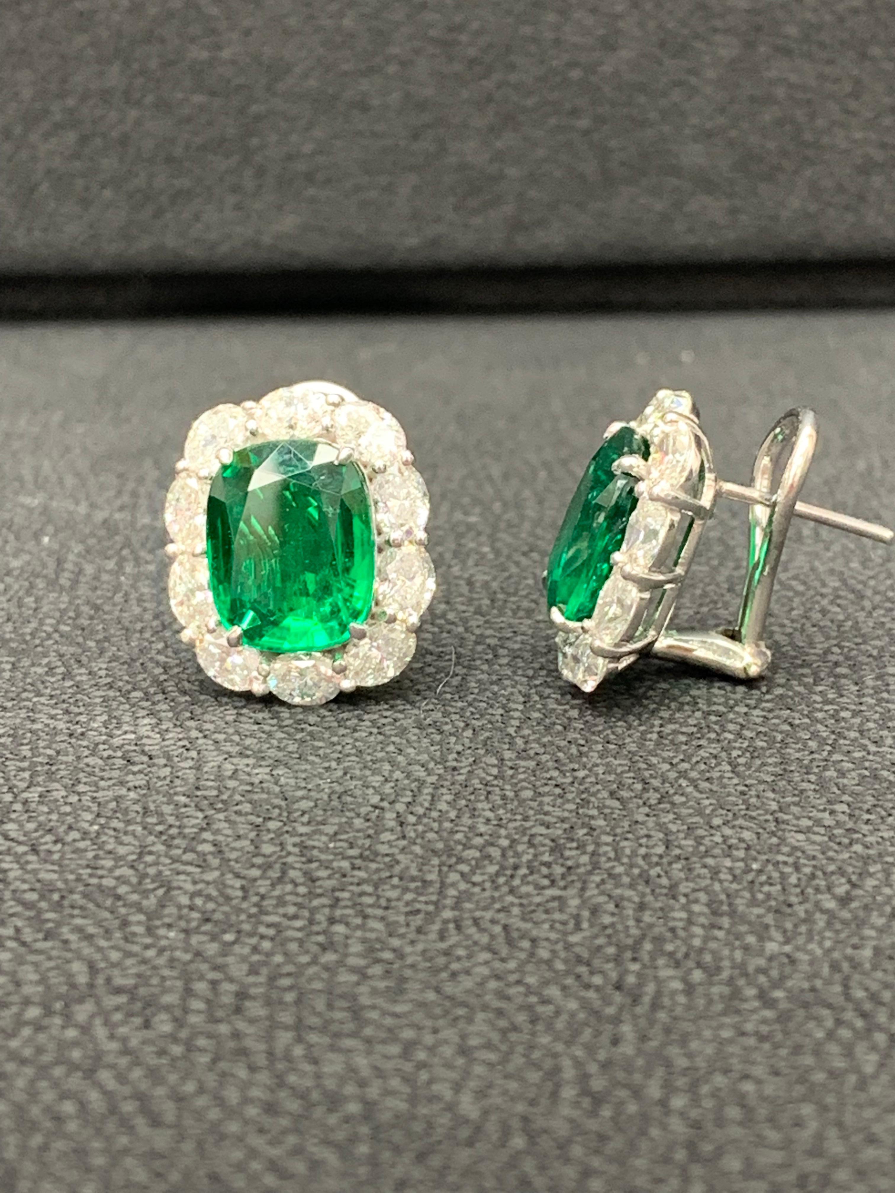 Showcasing two color-rich Cushion cut Lush Green Emeralds weighing 7.77 carats total, surrounded by a single row of oval cut brilliant diamonds. 20 Accent diamonds weigh 3.70 carats total. Set in 18 karats white gold. Omega Clip with the