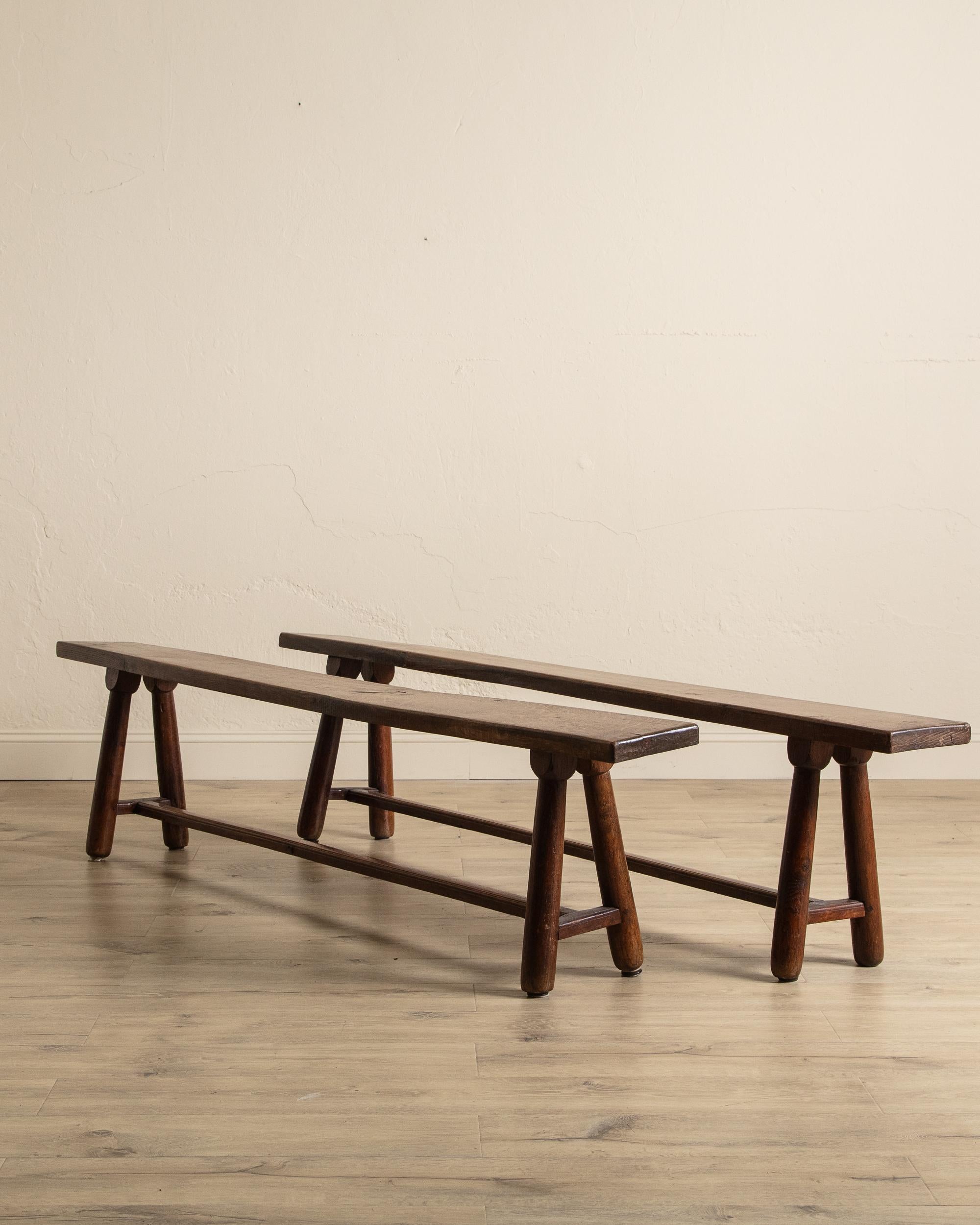 This petite oak bench offers rustic simplicity and timeless functionality, defined by its slender, elongated form and gently rounded legs. A single stretcher connects the base, providing both stability and a subtle sense of balance. Its versatile