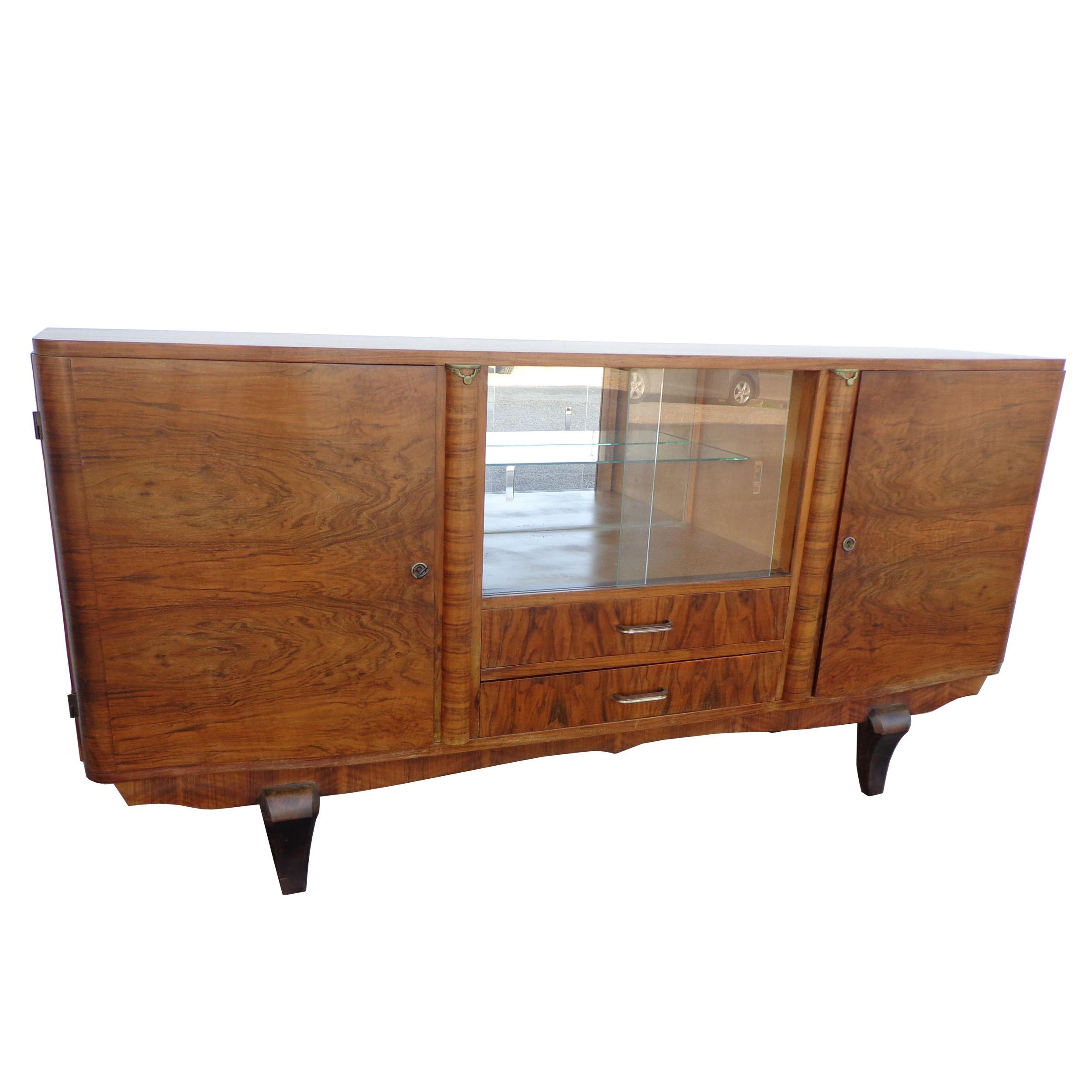 Vintage Art Deco cocktail cabinet
English cocktail bar cabinet of burled walnut from the Art Deco era.
Two storage cupboards, each with two shelves and a locking mechanism with key.
The center opens to a bar cupboard with a mirrored back and