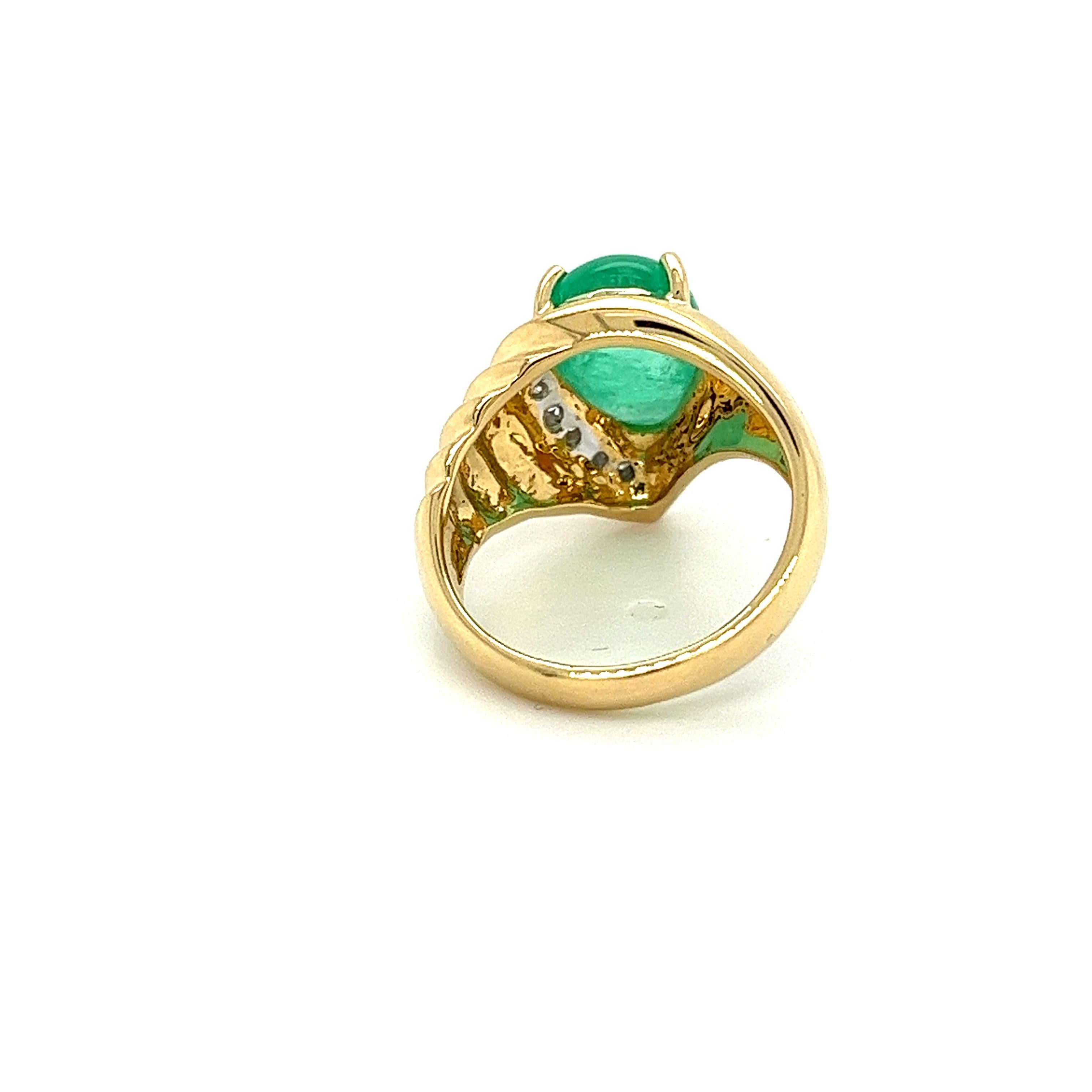 18K yellow gold ring featuring a7.81 carat pear shaped cabochon cut natural green emerald as the center stone. The 7.81 carat emerald showcases a beautiful green hue, and smooth cabochon cut. Adorned with 0.29 carats in round cut diamonds. This ring