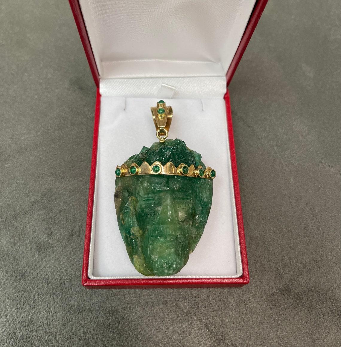 Showcased is a rare, rough emerald crystal pendant. 57 total carat weight of genuine, rough, Colombian emerald crystal is perfectly capped by smooth yellow gold and cabochon emerald bezel. The piece is semi-transparent and has a rich green color