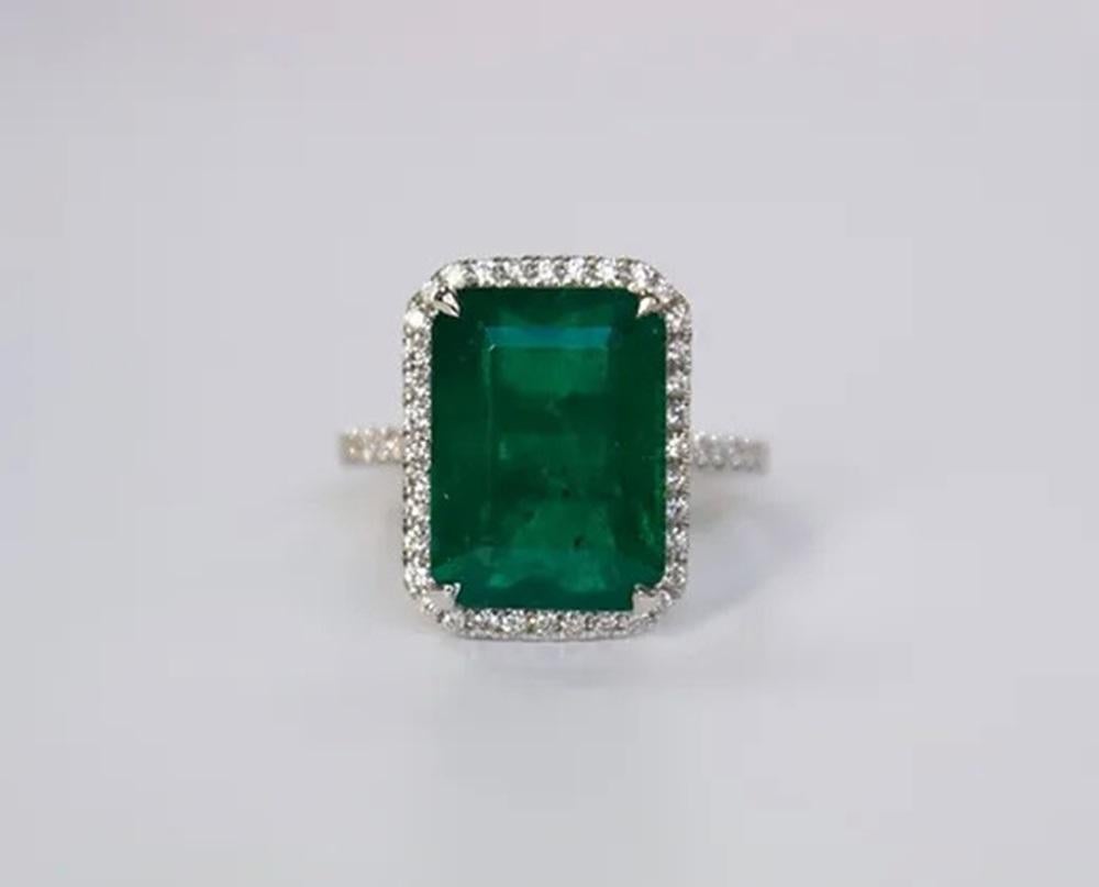 Emerald Weight: 7.84 ct, Measurements: 14x10 mm, Diamond Weight: 0.35 ct, Metal: 18K White Gold, Metal Weight: 5.51 gm, Ring Size: 6.5, Shape: Emerald-Cut, Color: Vivid Green, Hardness: 7.5-8, Birthstone: May, Origin: Zambia