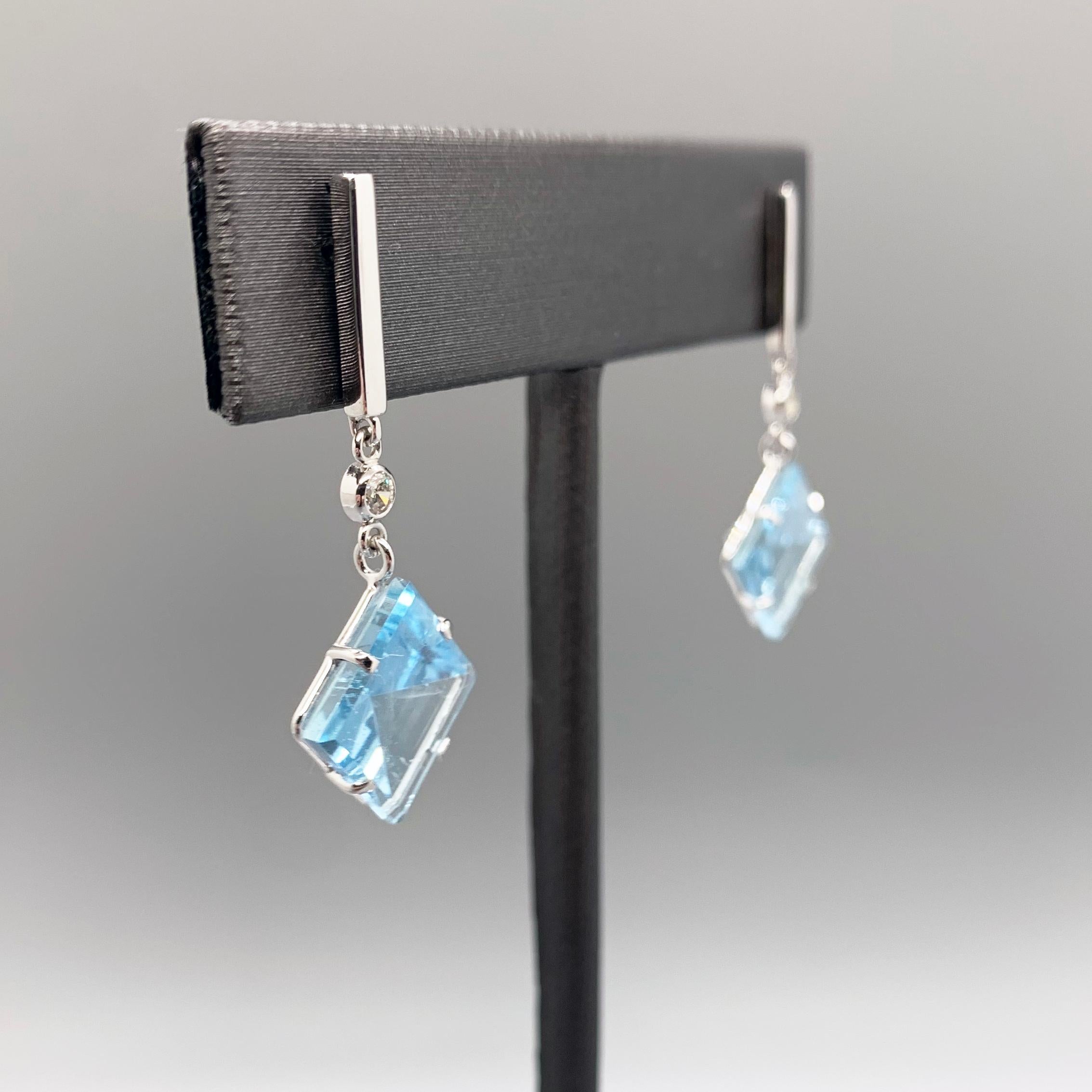 This earring set was designed to highlight the geometric beauty of it's center piece: a pair of mirror cut aquamarines with a 7.88 total carat weight. The mirror cut plays up the gemstones' natural refractive properties, creating an interesting