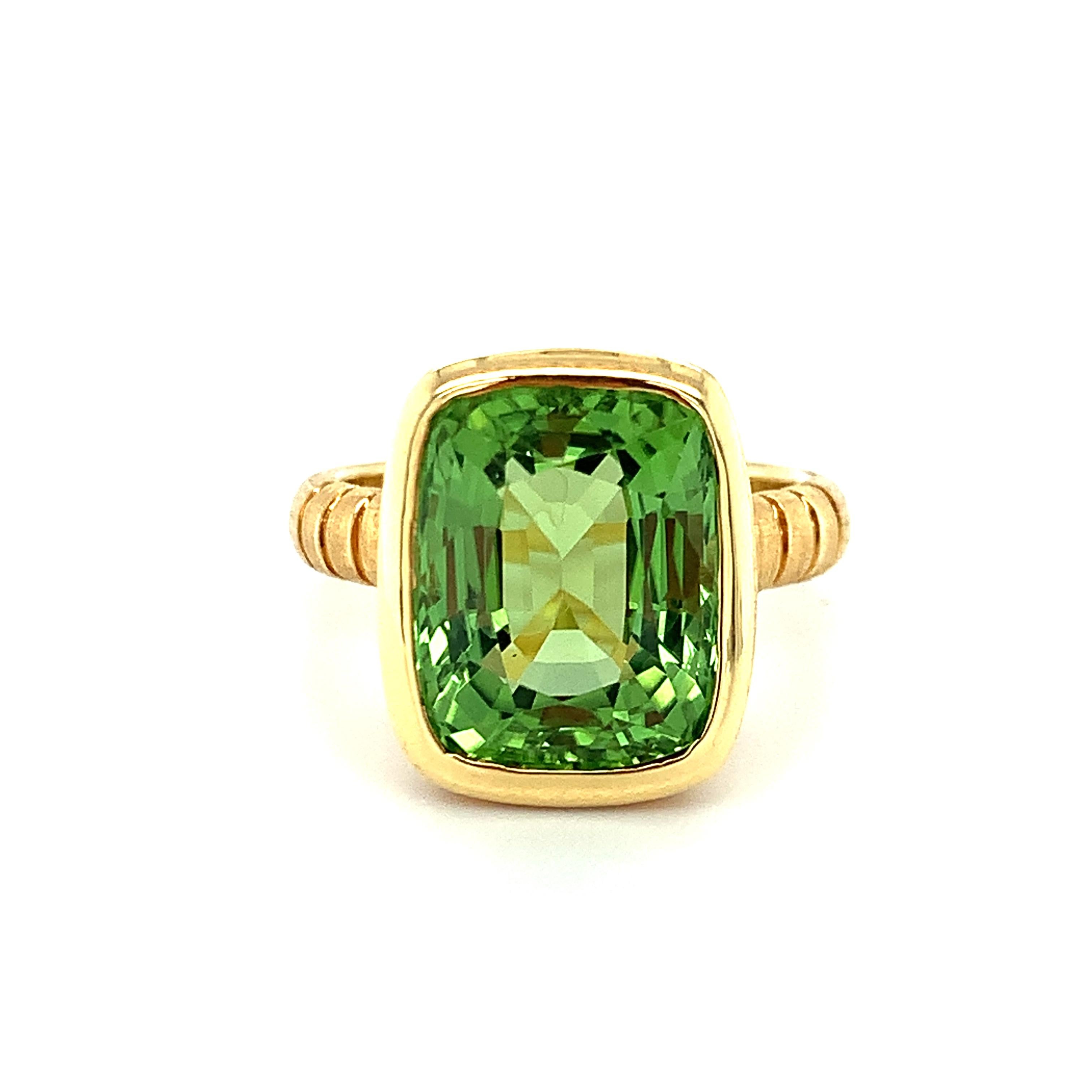 This 18k yellow gold handmade ring features a luscious grass-green peridot weighing 7.88 carats faceted in a handsome cushion shape. The peridot has been bezel set in one of our signature rings, designed to showcase a fine quality gem that deserves