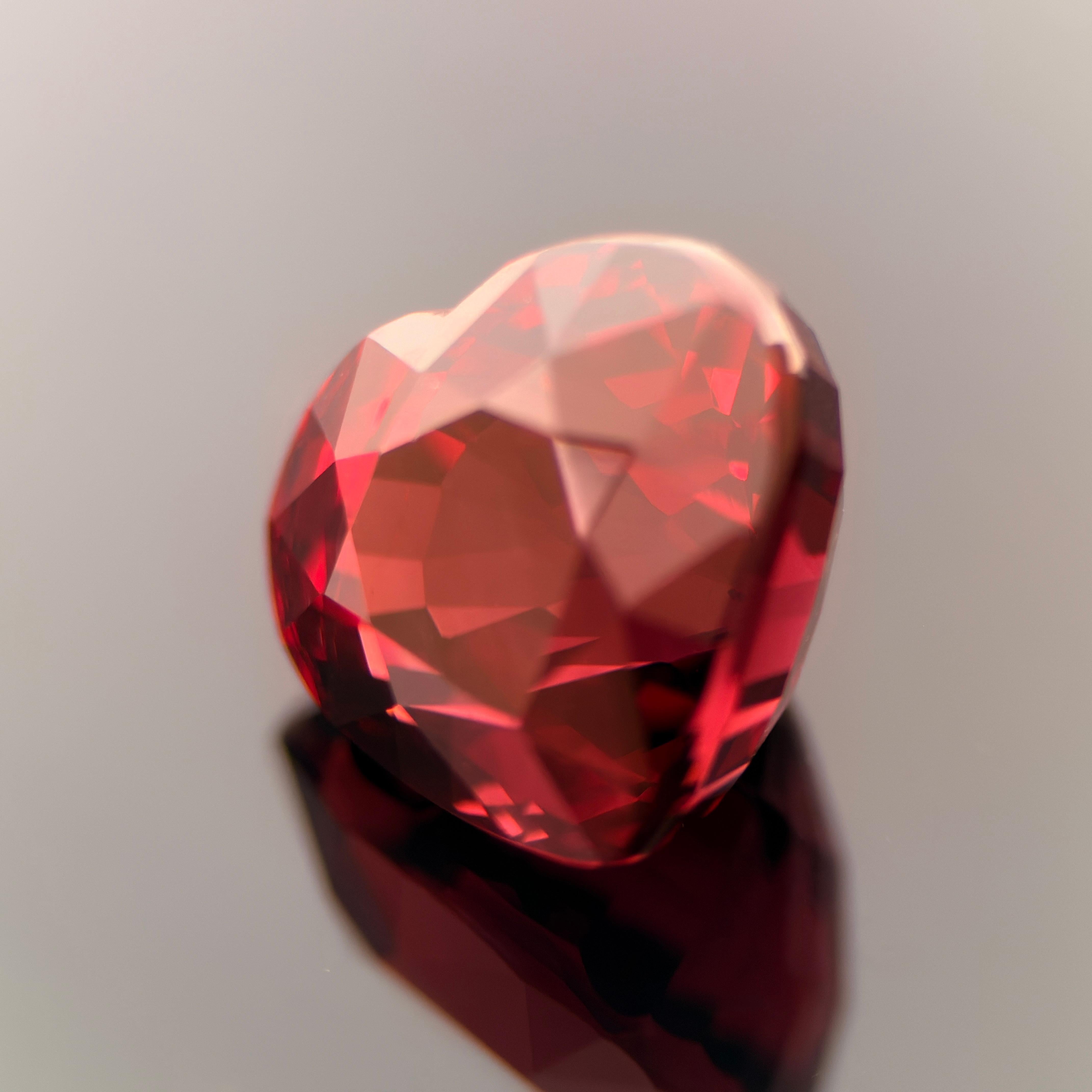 A stunning natural garnet weighing 7.89 carats, beautifully fashioned into a heart cut with striking depth and fiery brilliance.
The gem displays a rich, vivid red color with subtle flashes of magenta — a hallmark of premium-quality