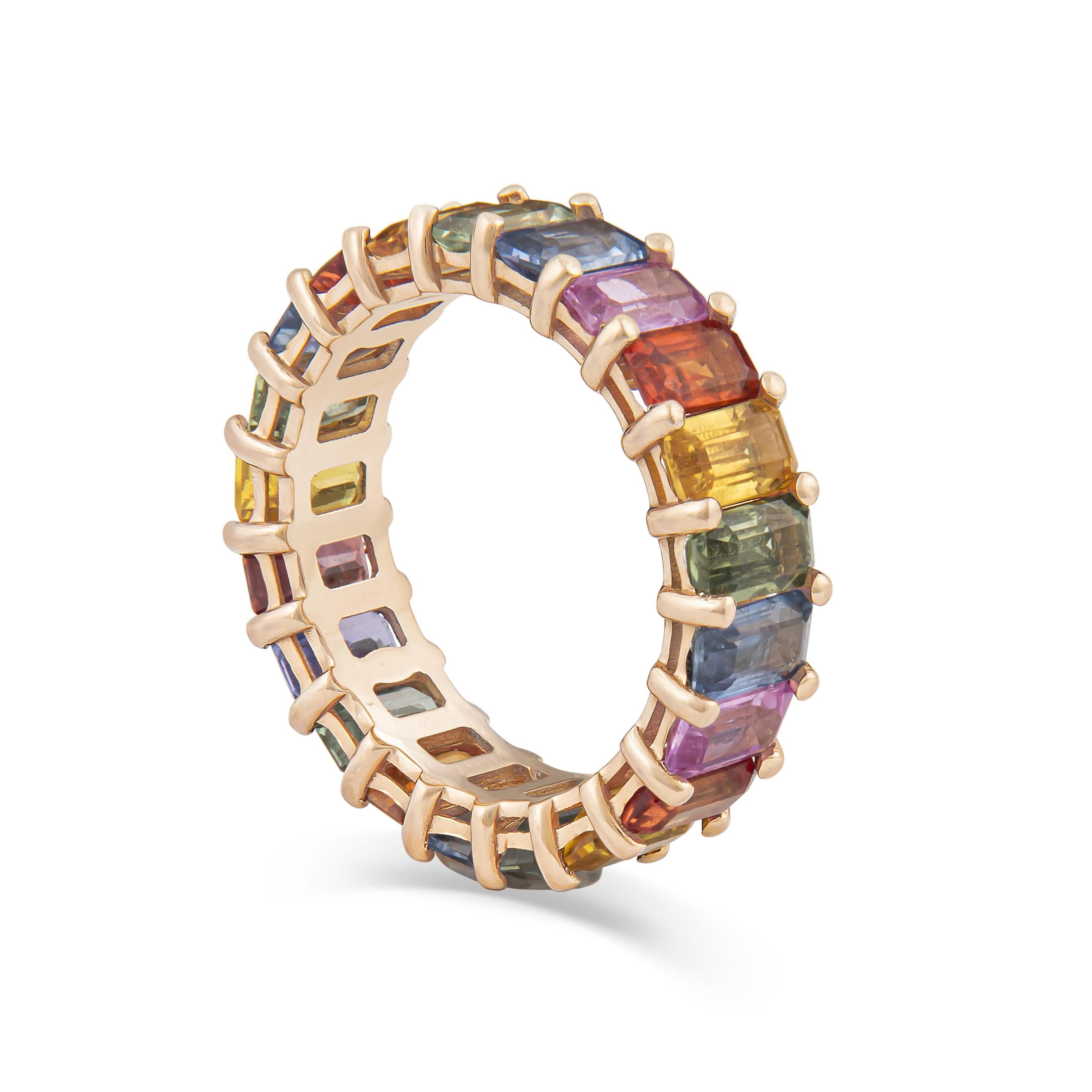 This beautiful eternity band features 7.93ct total weight in multi-colored emerald cut sapphires, set in an 14kt rose gold ring. The ring is currently a size 6, made by our on-site master jewelers. It is a simple way to add colored stone jewelry to