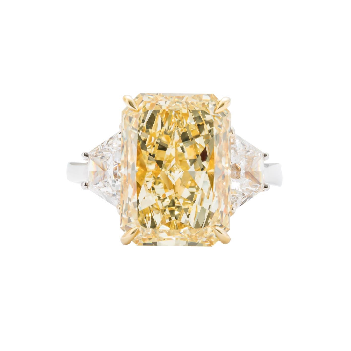 Custom Platinum and 18 karat yellow gold three stone ring featuring one radiant cut Fancy Yellow Diamond weighing 7.95 carats with color and clarity of FY VS2; accompanied with GIA certificate #1186712477. Flanked by two trapezoid diamonds weighing
