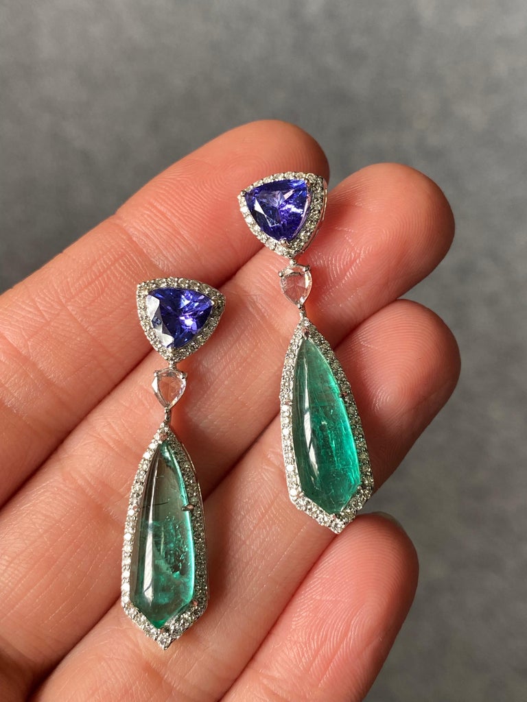 A pair of beautiful 7.96 carat Zambian Emerald and 2.04 carat Tanzanite dangle earrings, with 1 carat VS quality colorless Diamonds set in solid 18K White Gold. The special shield-cut cabochon Emeralds and trillion shaped Tanzanite both are