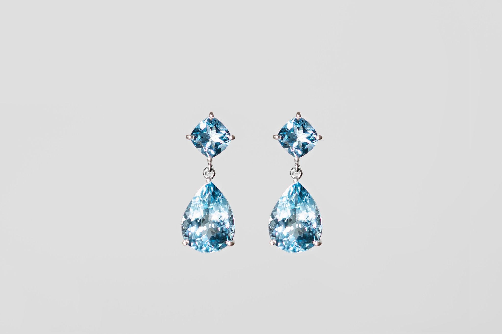 Elevate your style with these glamorous drop earrings. Handmade using recycled sterling silver and Swiss Blue Topaz. The pear-shaped stone is 6 carats, and the square top stone is 1ct. They are exceptionally well cut and crafted using upcycled Swiss