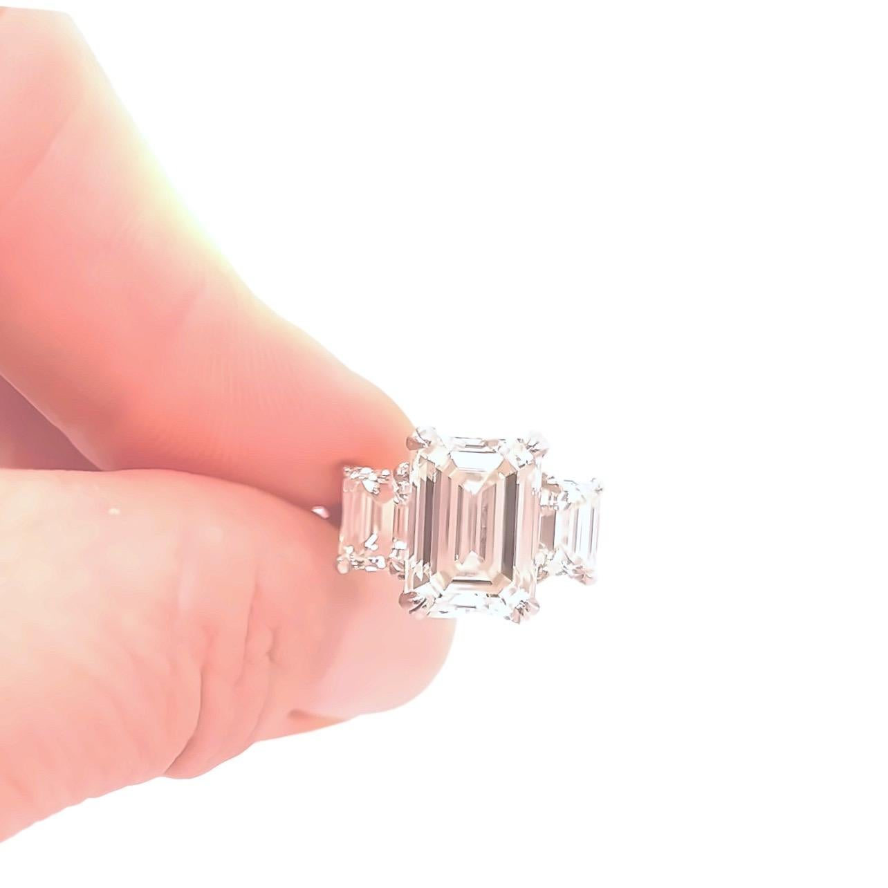 Classic 3 stone engagement ring featuring a 5.01ct Emerald cut Diamond with GIA certificate accented by two additional emerald cut side stones each weighing almost 1ct each all set in platinum. The center stone is accompanied by a GIA Report and the