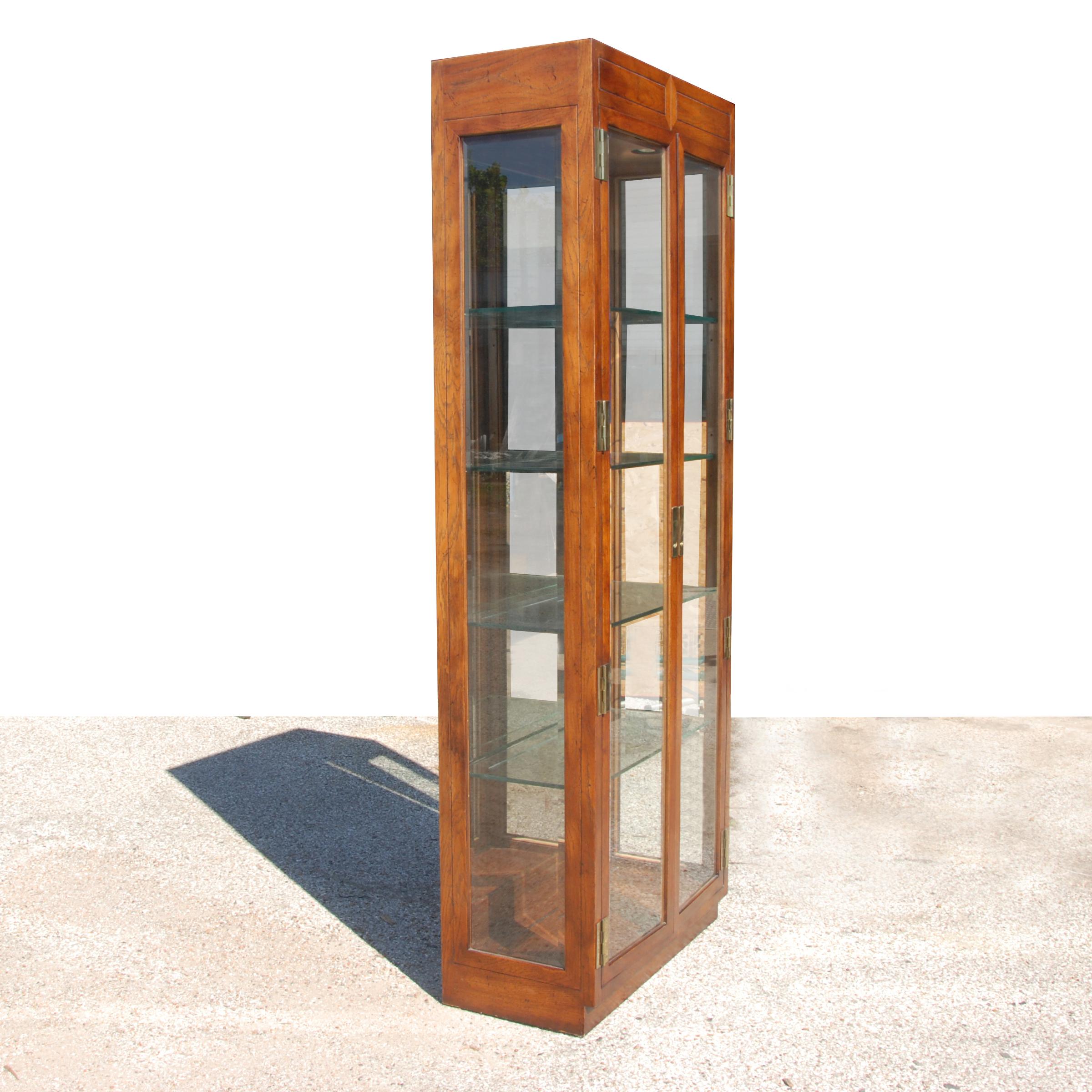 7ft Henredon scene one Curio cabinet with walnut and brass

Done in a campaign style, from the Scene One from Henredon. Features brass accents, and four glass shelves. 
Has adjustable glides on bottom.