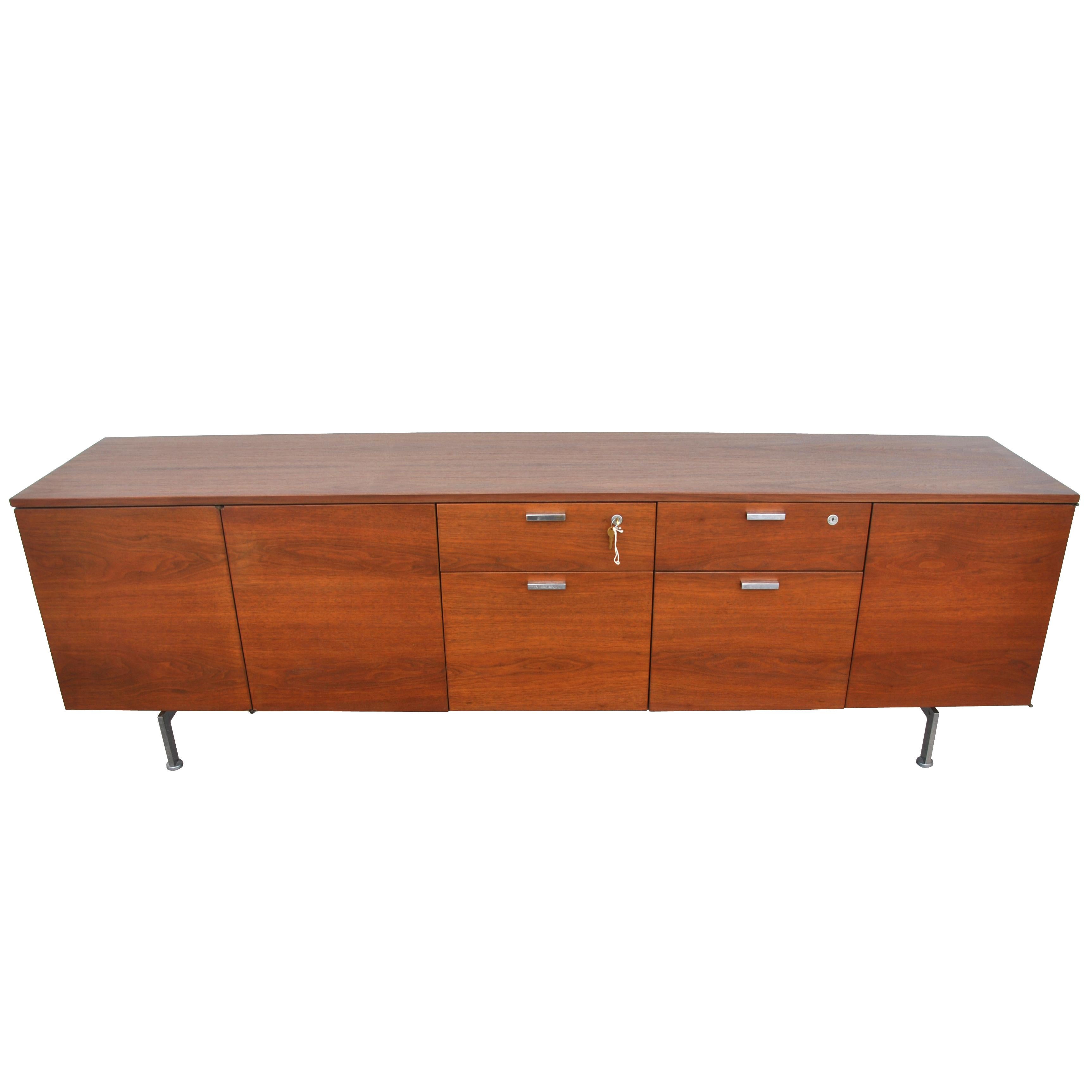 Vintage midcentury credenza by Robert John

Walnut with chrome legs. Chrome pulls. Two file drawers and two open cabinets with adjustable shelves. One exterior door folds back onto the stationary door when shelving is exposed. Locking mechanism