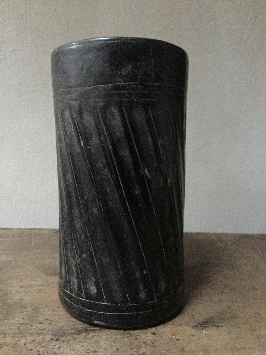 Grand vase cylindrique en céramique de la culture maya, Dzibanché, Quintana Roo, Mexique Période classique, 550 à 950 après J.-C. Sa glaçure noire accentue les flancs godronnés qui forment un décor linéaire répétitif. Trois cercles sont incisés sur
